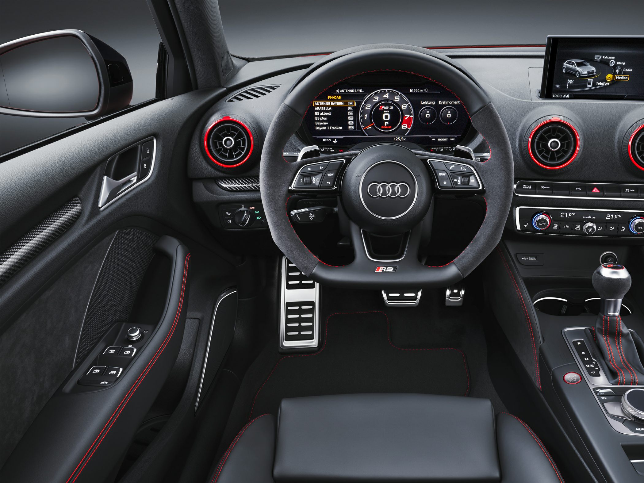 Sporty steering wheel, digital cockpit display, red accent vents, modern driver controls