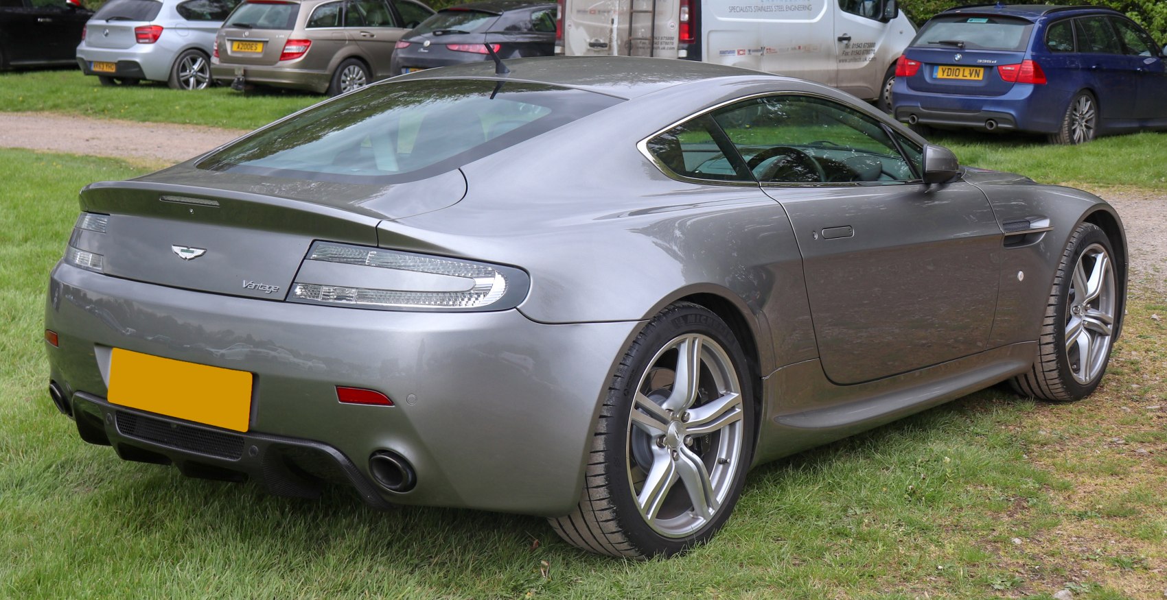 Rear and side view of a sleek sports coupe with alloy wheels and dual exhaust.