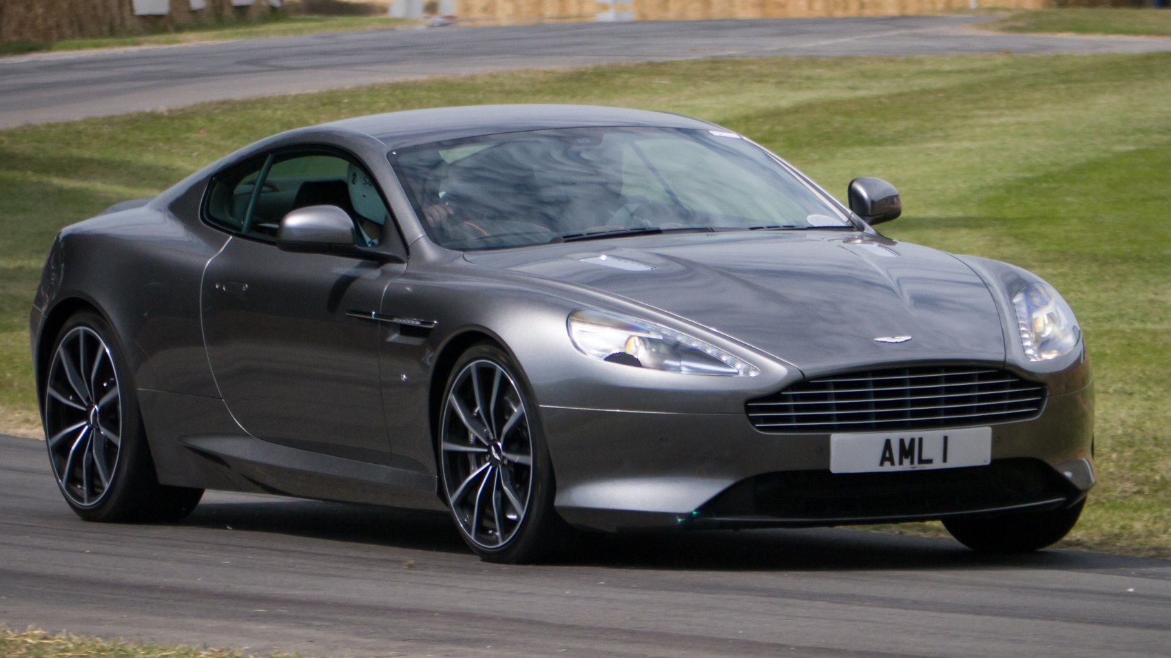 Front side view of a sleek silver coupe with alloy wheels on a paved road.
