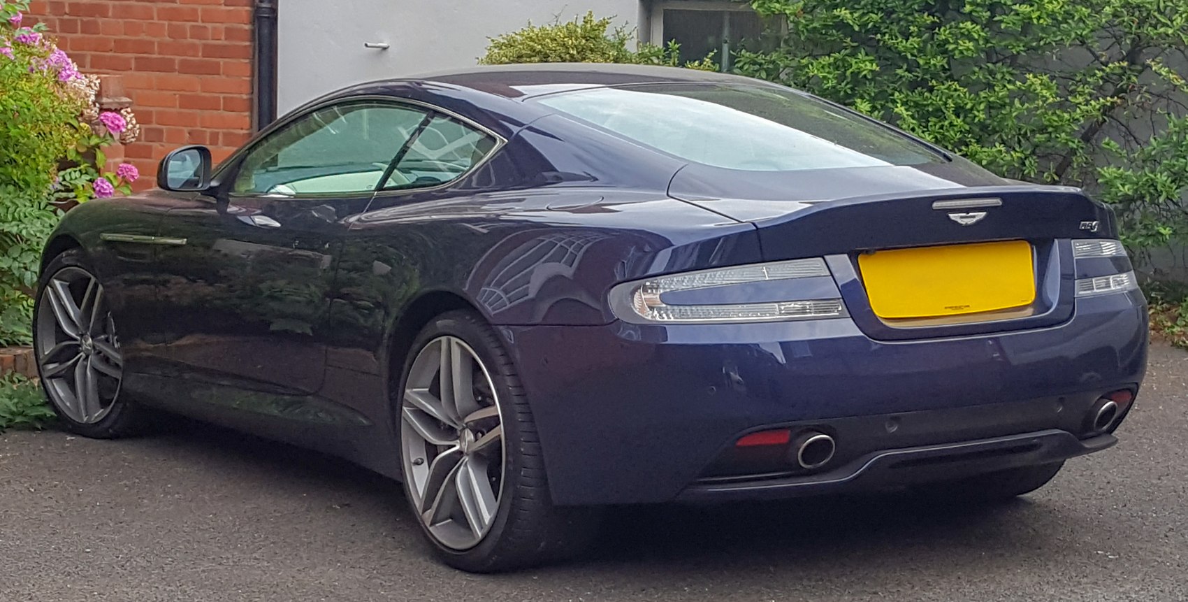 Rear profile with dual exhausts and alloy wheels of a facelifted sports coupe