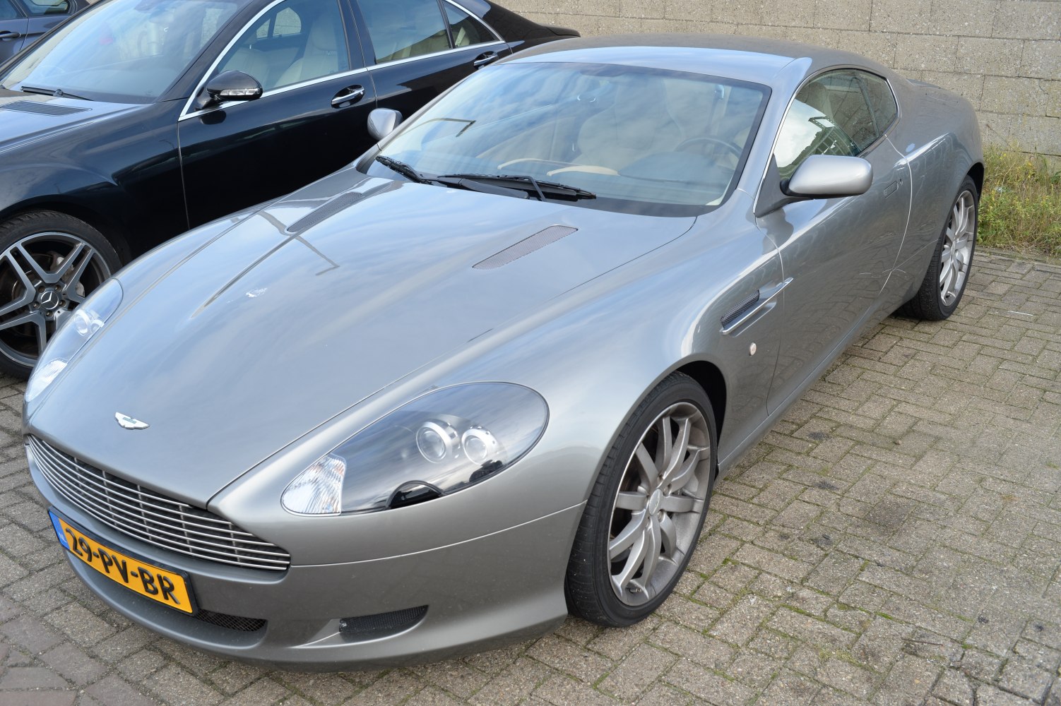 Front and side view of a sleek metallic silver grand tourer with aerodynamic vents and distinct headlight design