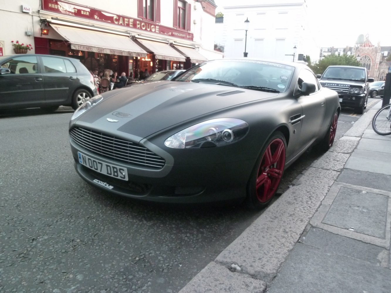 Front grille and red alloy wheels of a matte black coupe