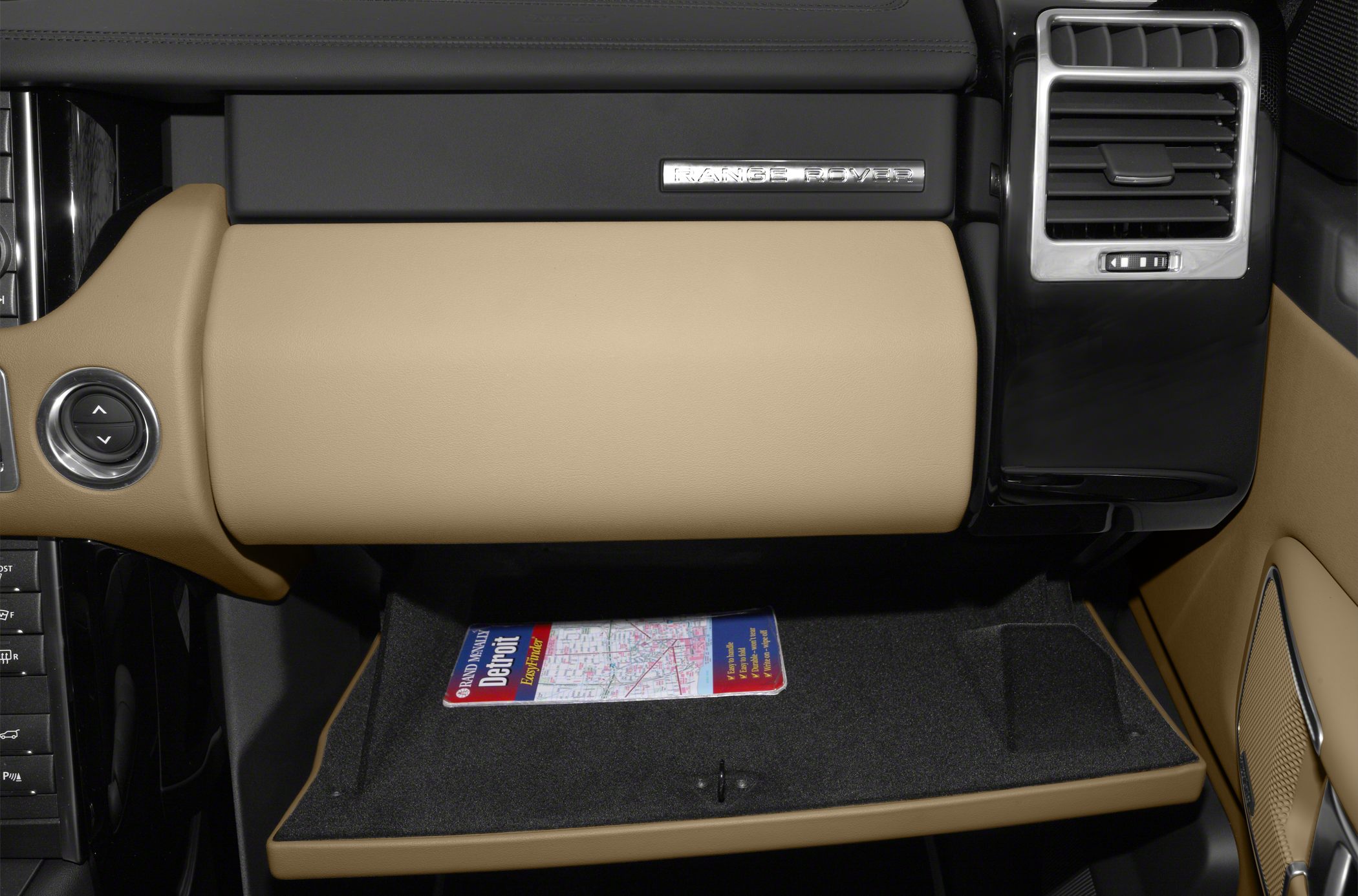 Open glove box with tan leather dashboard and air vent.