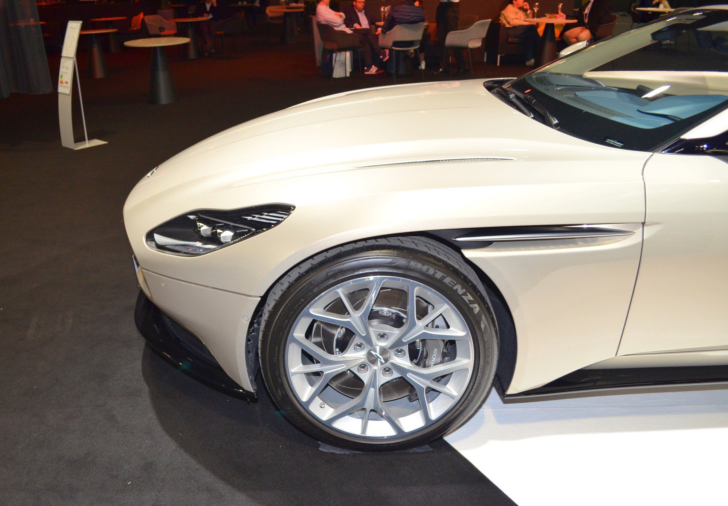 Front alloy wheel with Potenza tire and headlight of a luxury coupe