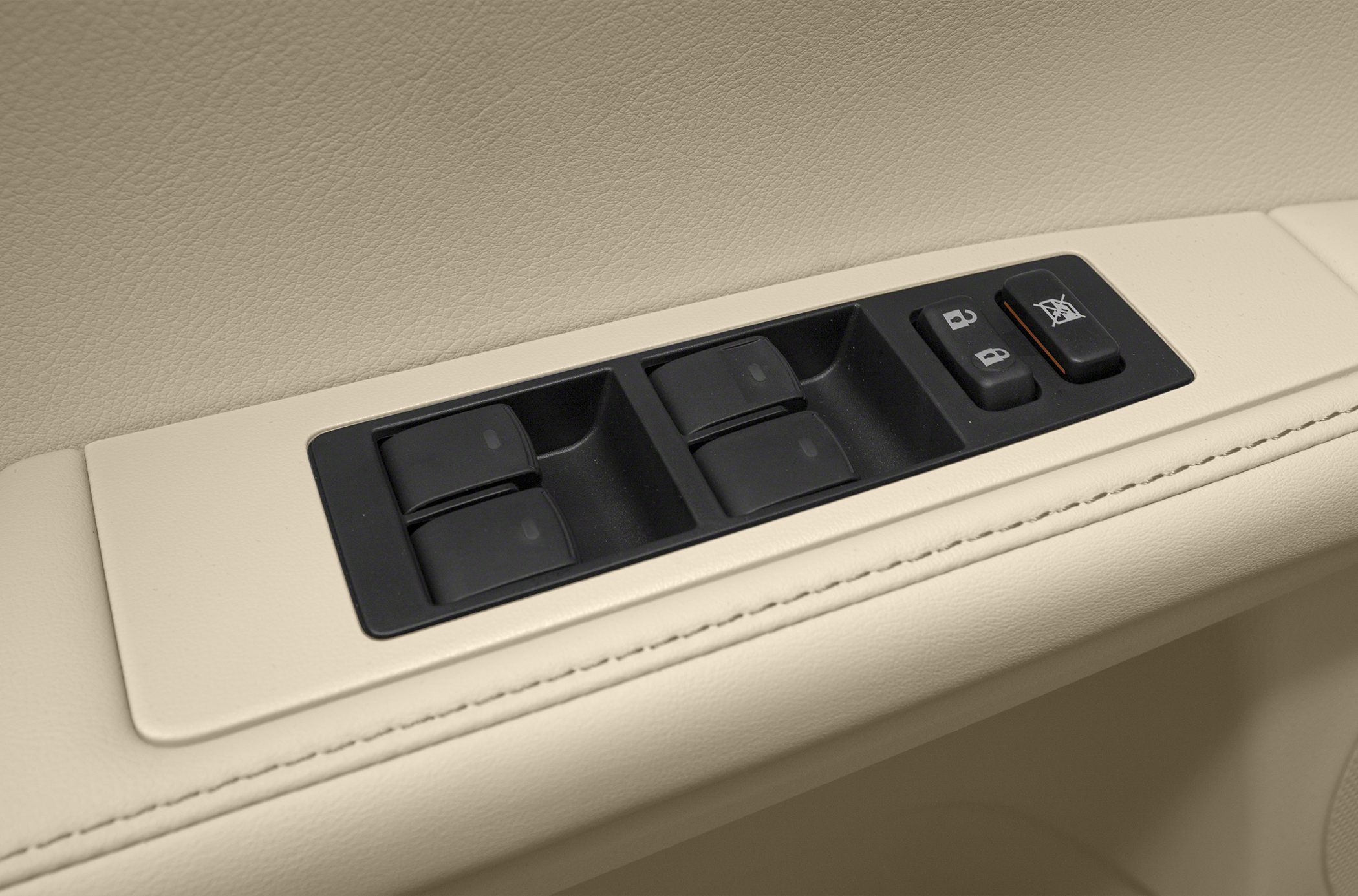 Power window switches and lock buttons on beige leather door panel