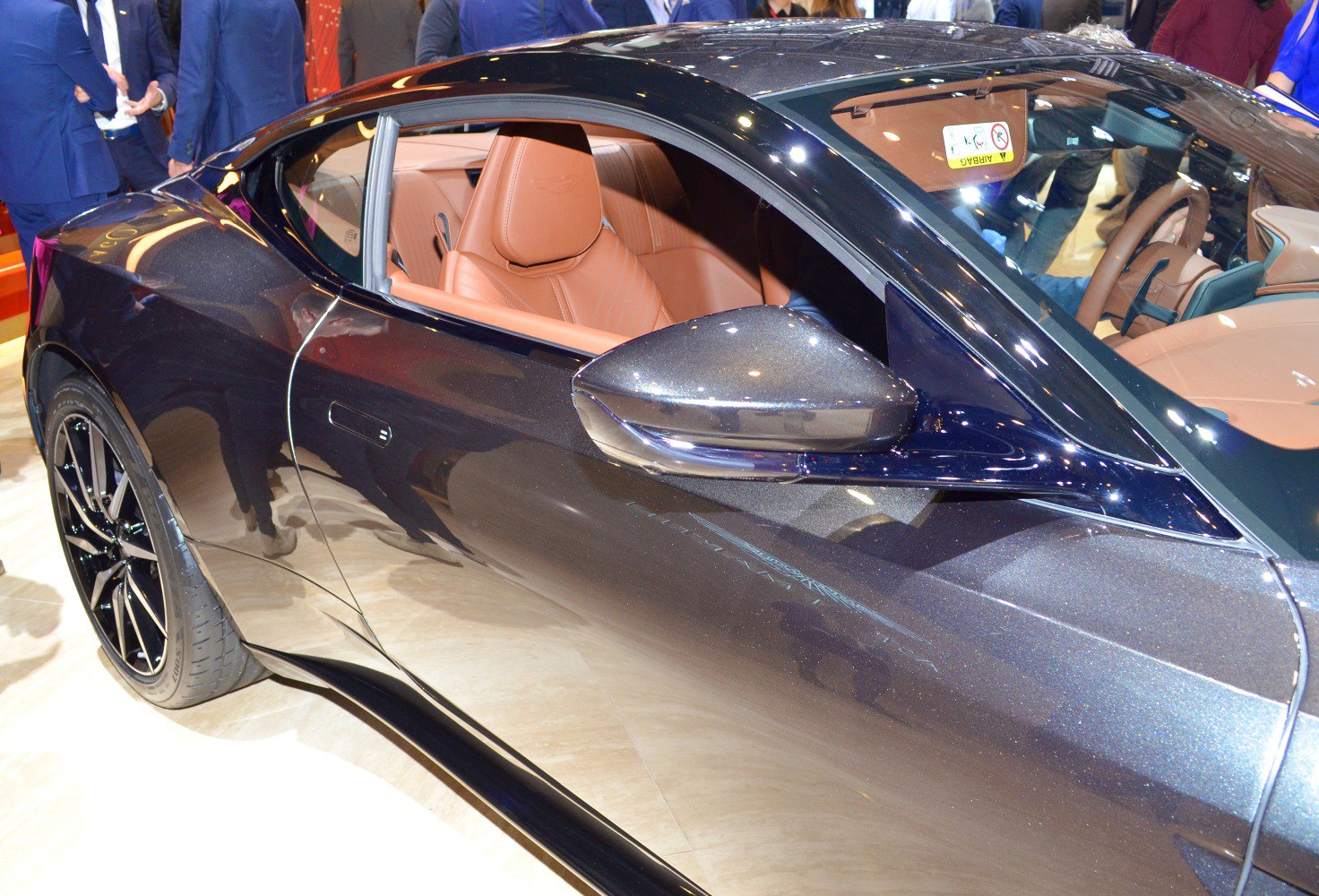 Glossy side mirror and tan leather interior with steering wheel visible