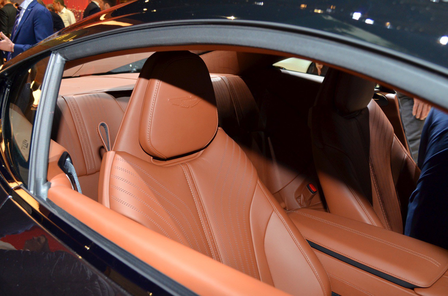 Tan leather perforated seats with embossed logo inside a luxury coupe.