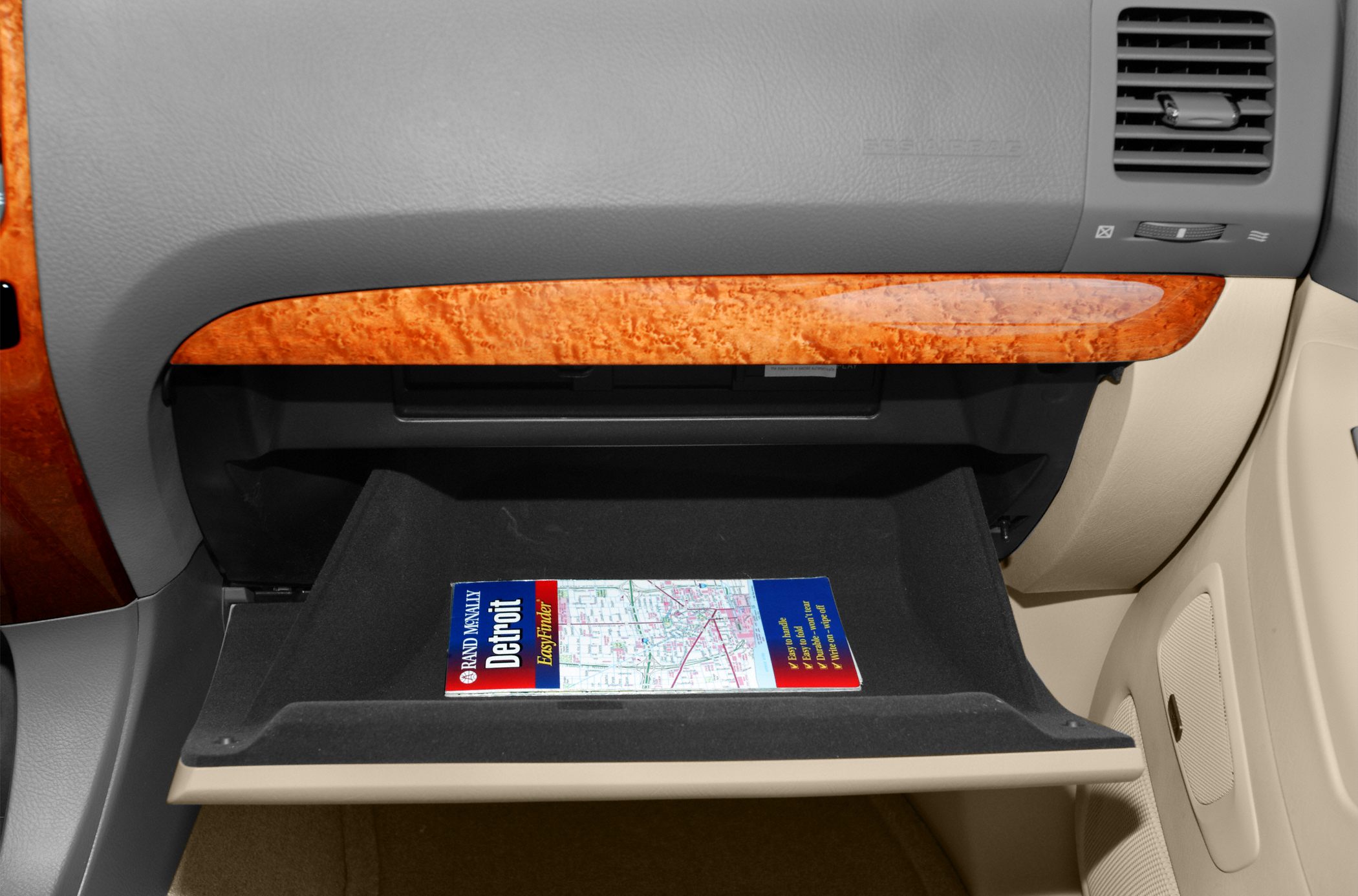 Open glove compartment with wood trim and a map inside