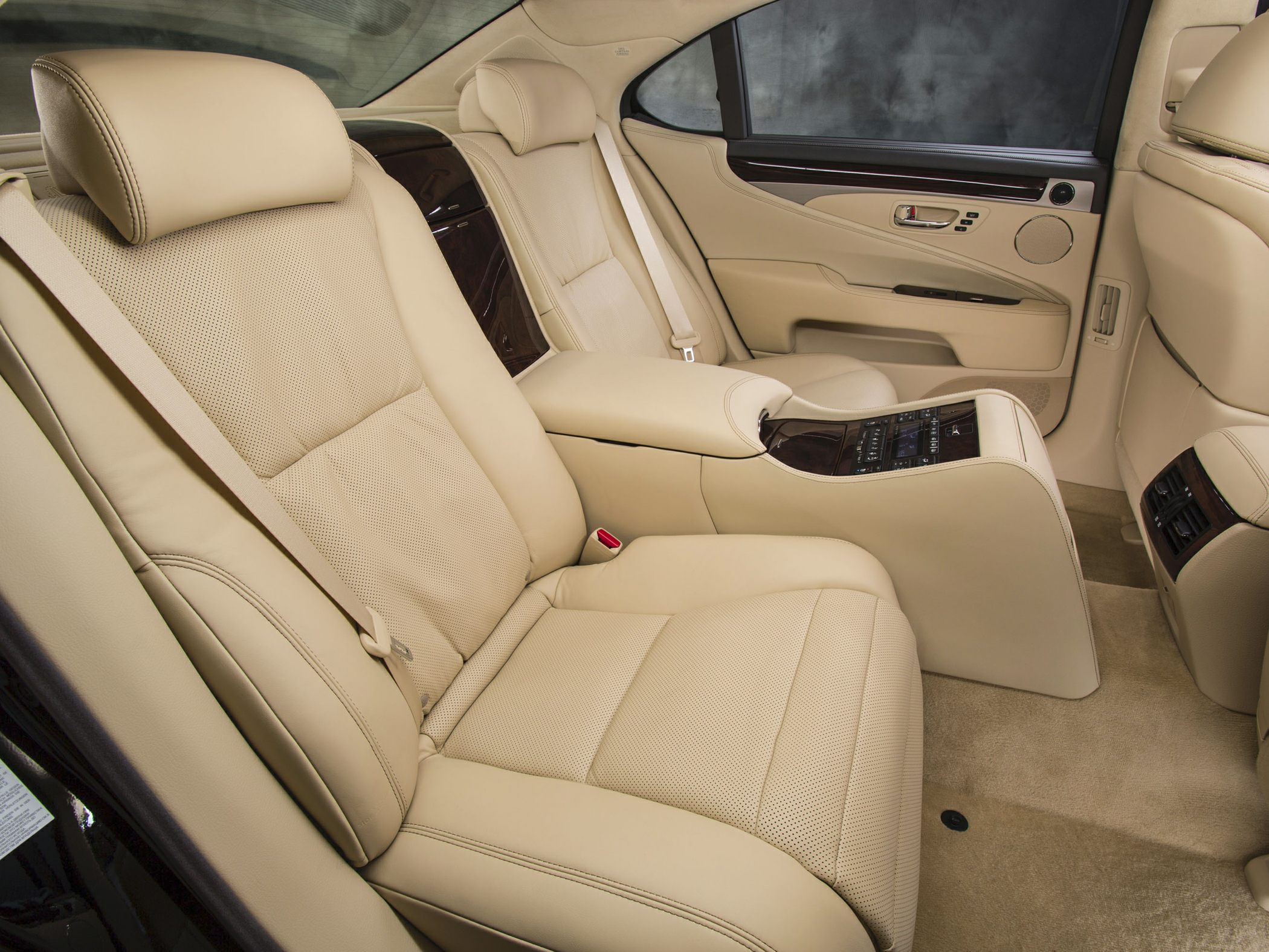 Beige leather rear seats and center console with controls in luxury car interior