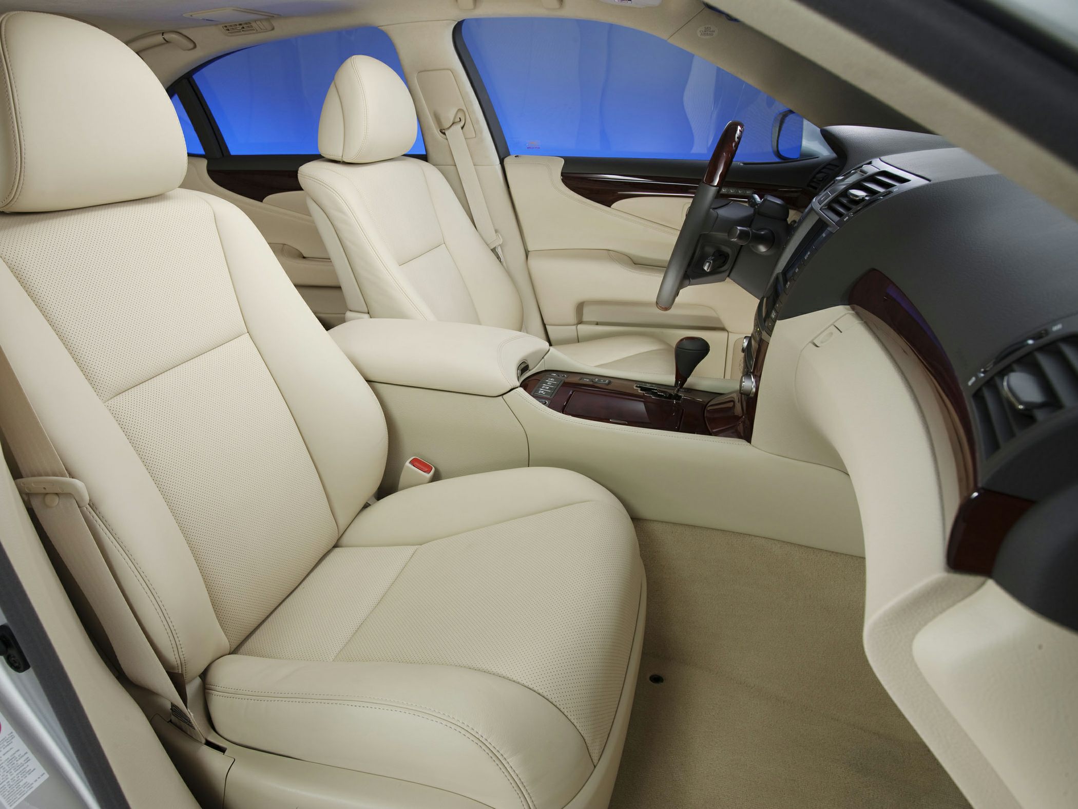 Beige leather seats with wood trim and automatic gear shift in luxury car interior