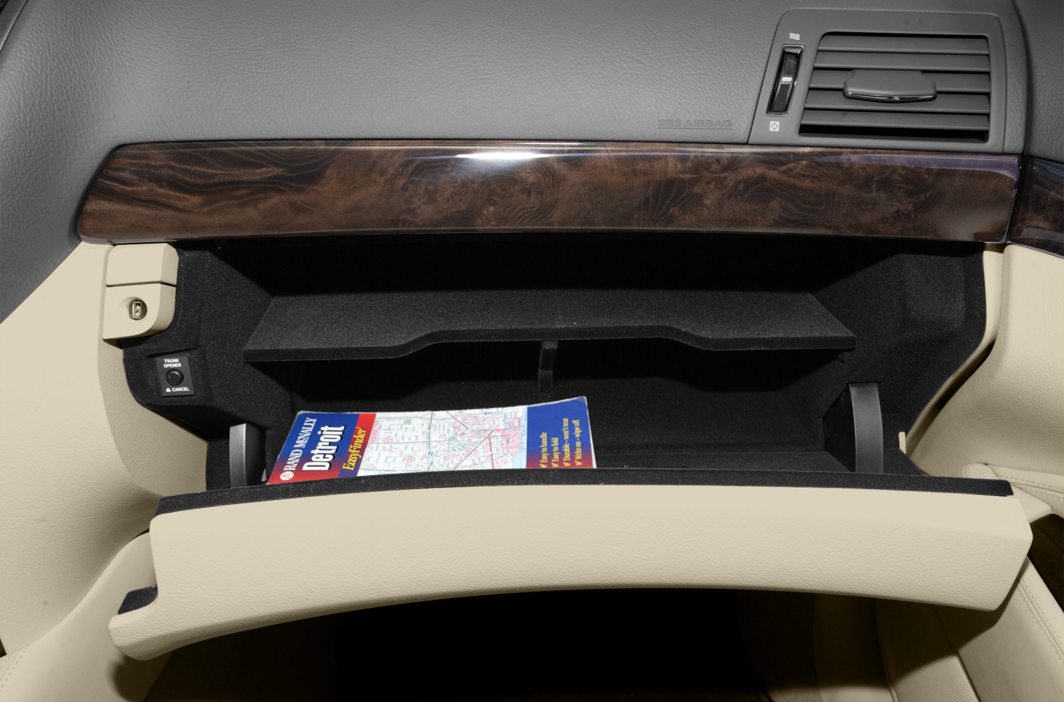 Open glove compartment with wood trim and beige leather interior