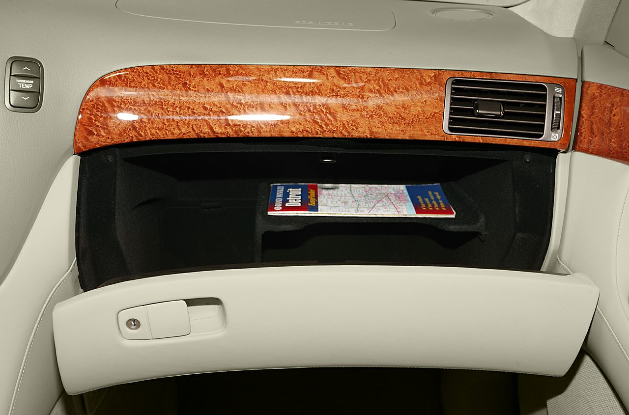 Open glove compartment with wood trim and beige leather interior.