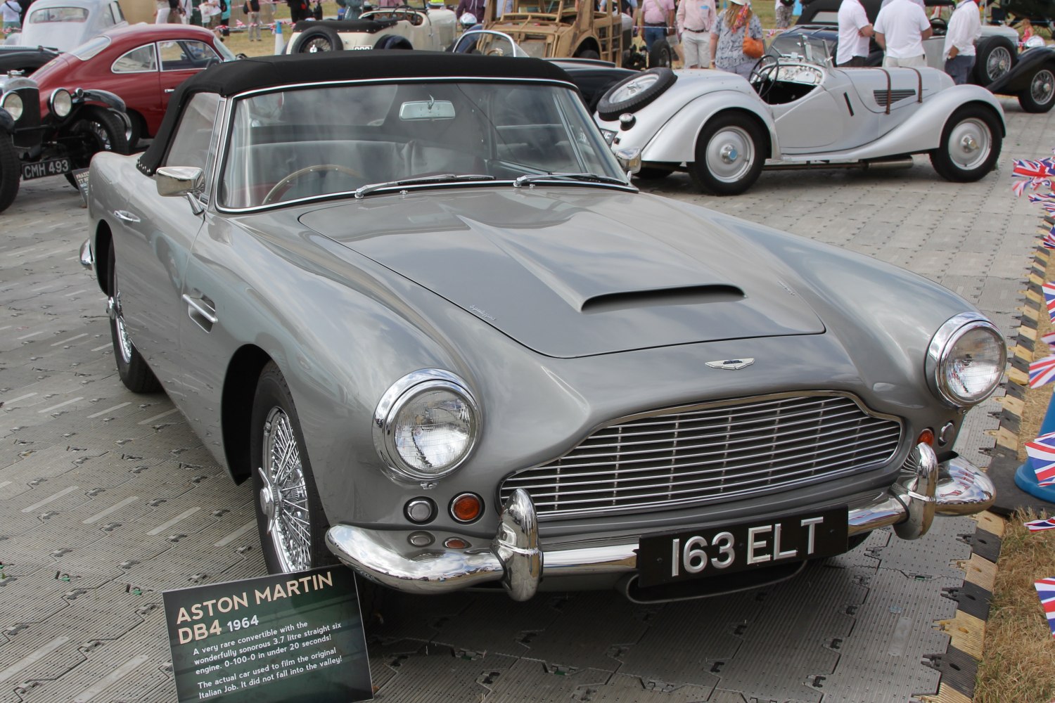 Front view of classic convertible car with grille, round headlights, and hood scoop