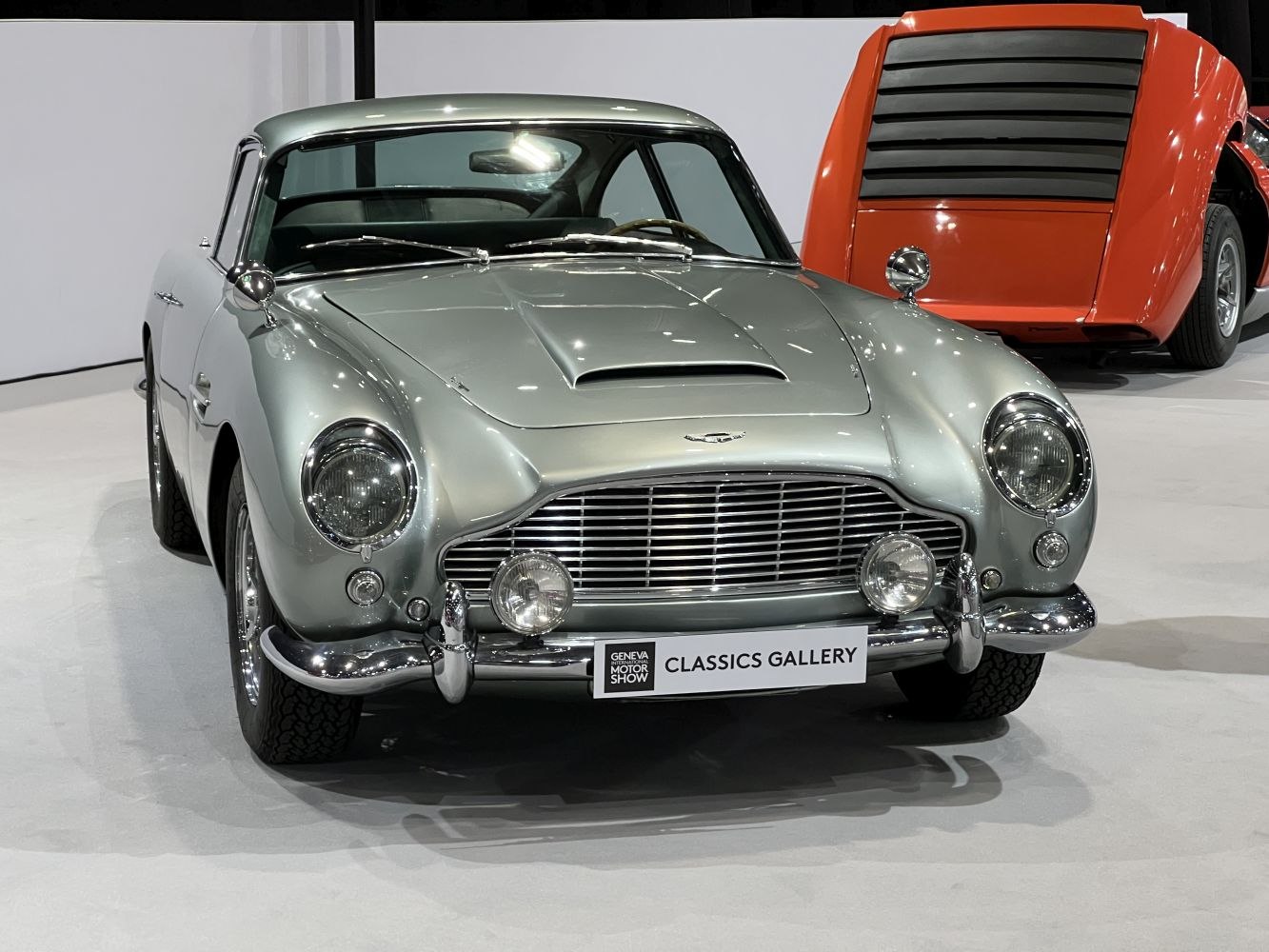 Front view with grille, round headlights, hood scoop, and chrome bumper