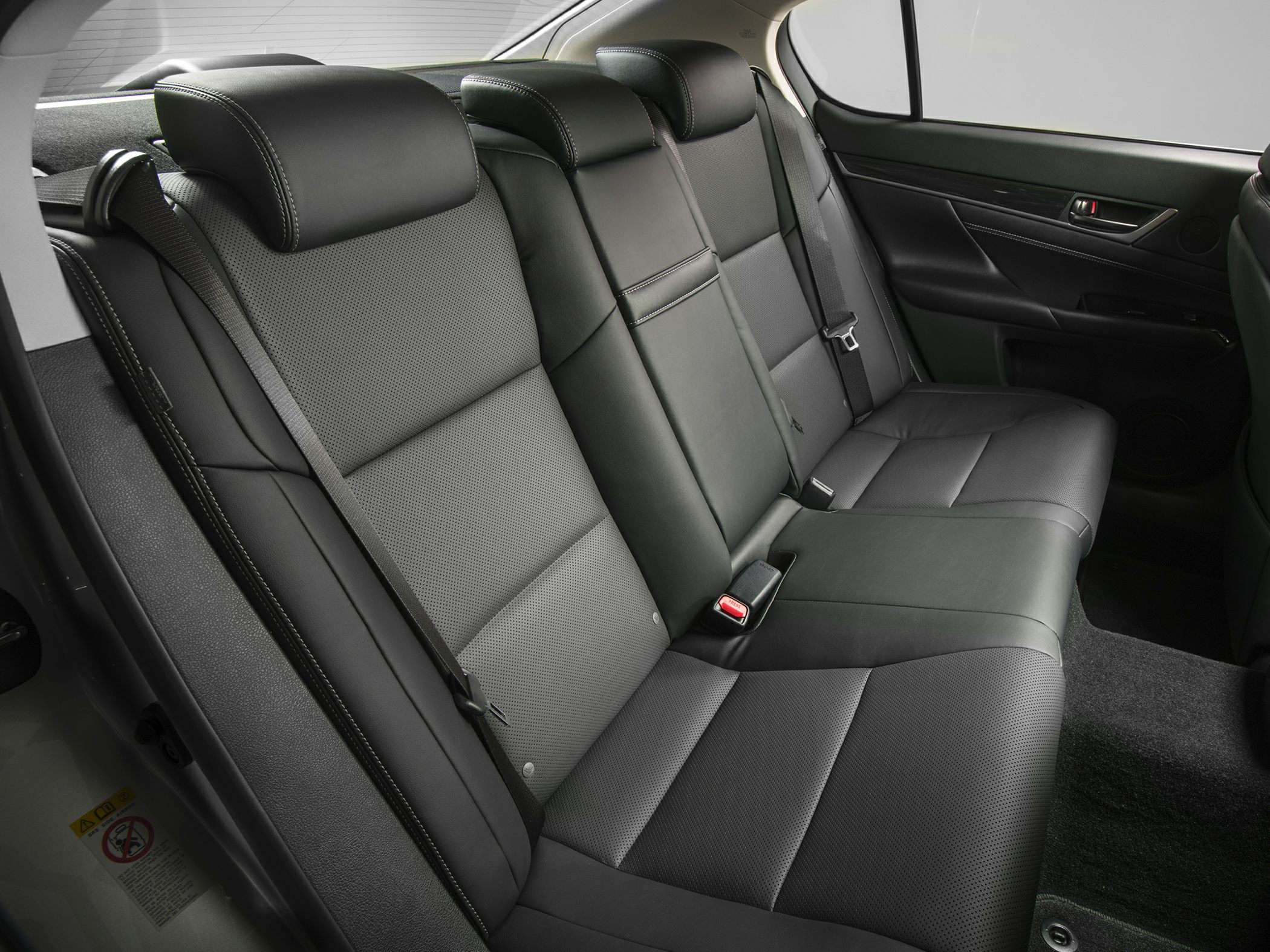 Black leather rear seat with three headrests and seat belts.