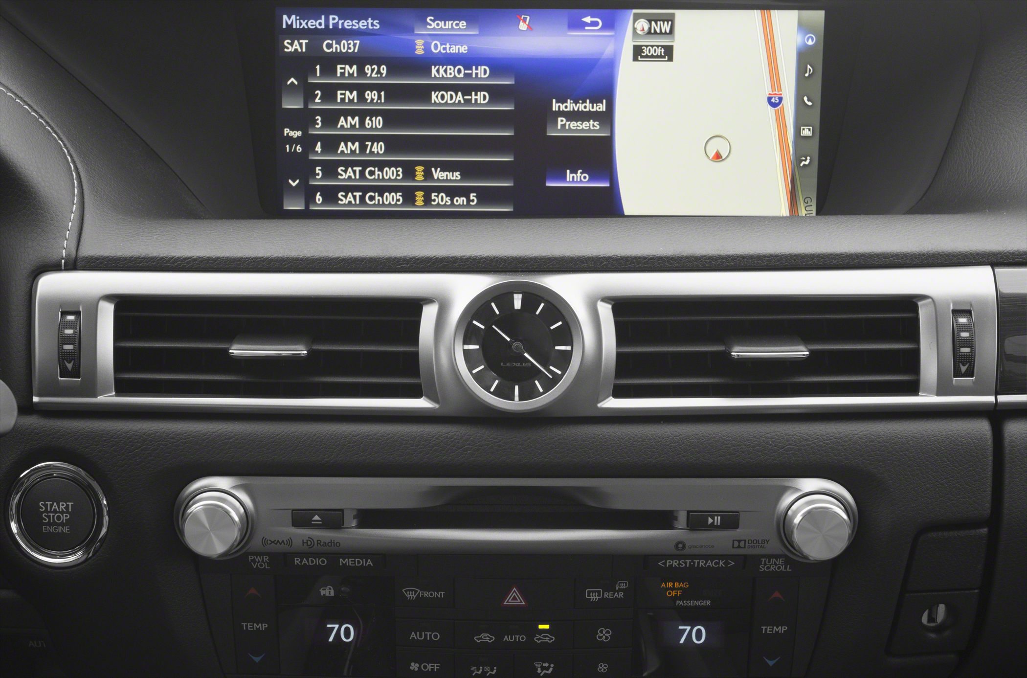 Analog clock centered between air vents and infotainment screen with navigation and radio presets