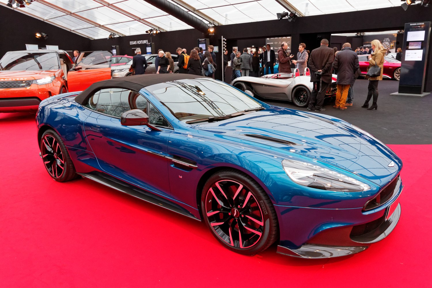 Blue convertible with black soft top and multi-spoke wheels on red carpet