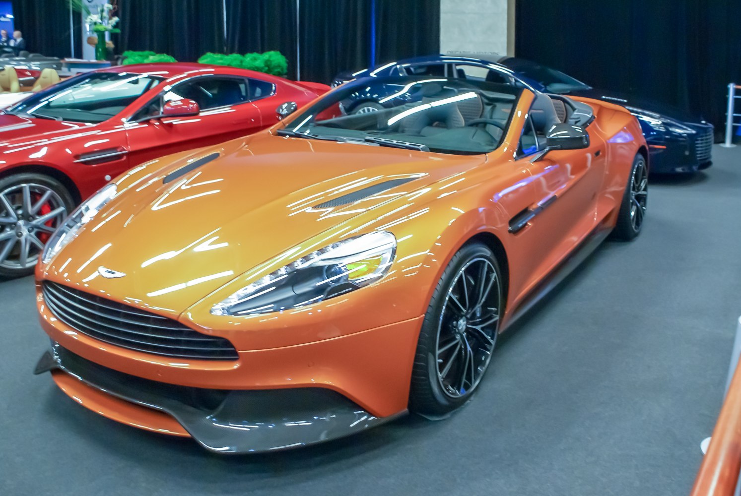 Orange convertible with sleek front, black rims, and open roof.