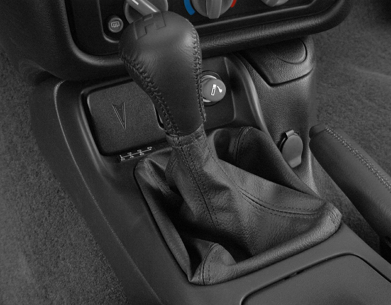 Manual gear shift lever and center console with controls and handbrake.