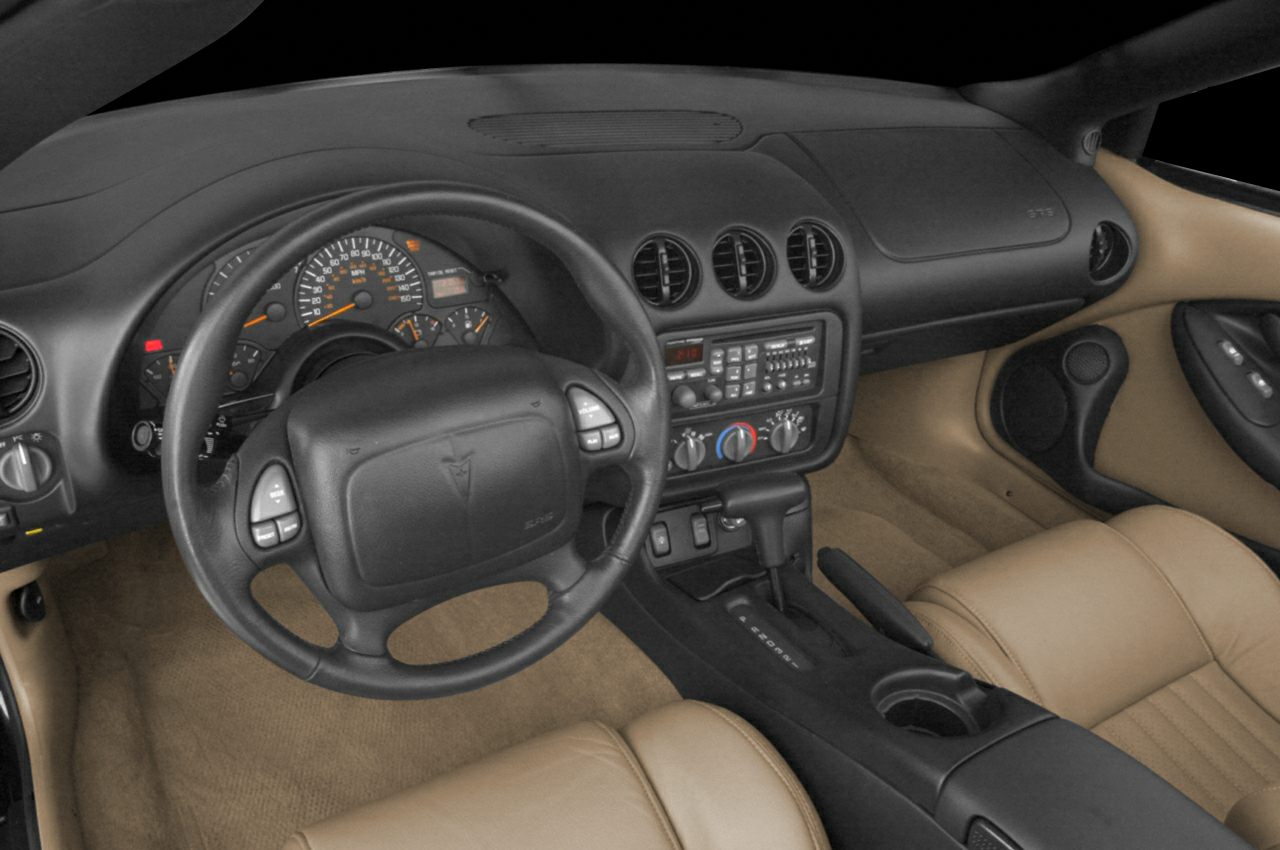 Car interior with dashboard, steering wheel, center console, and beige seats