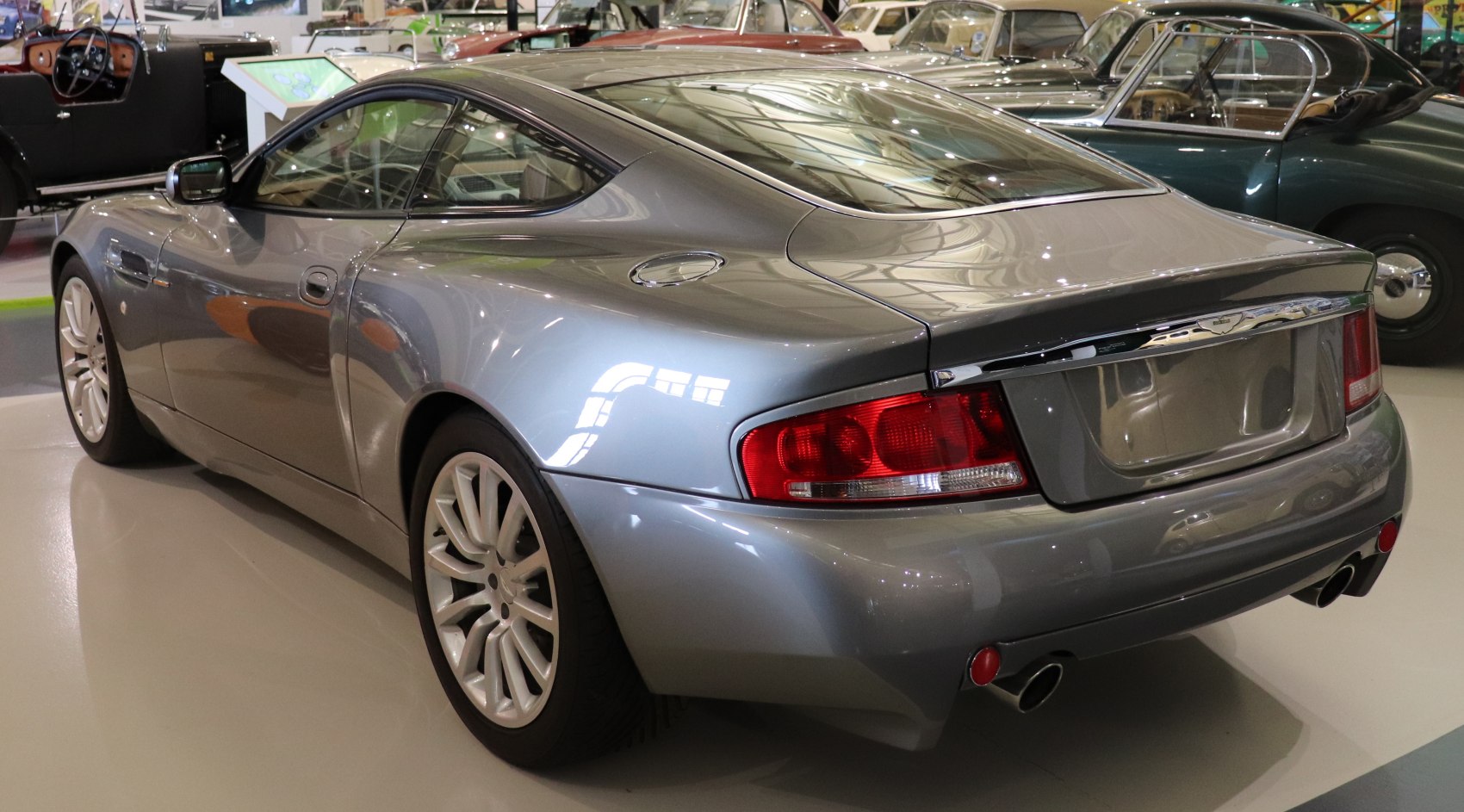 Rear and side profile of a streamlined sporty coupe with dual exhausts and alloy wheels.