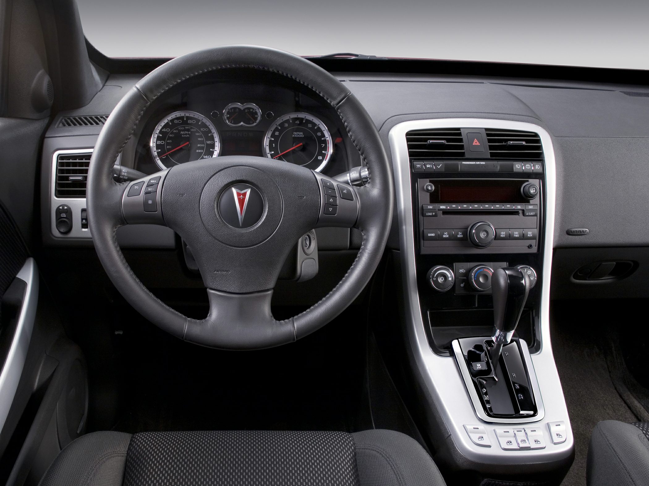 Leather steering wheel with dashboard and center console featuring gear shift and controls