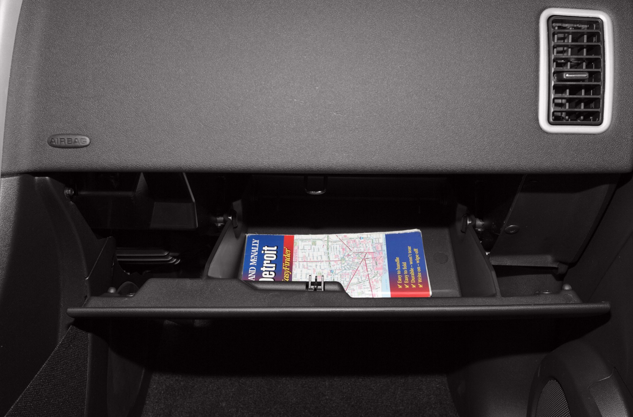 Open glove compartment with folded map inside car dashboard