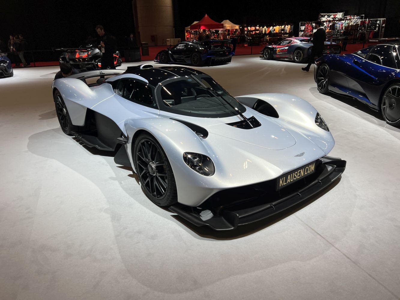 Silver aerodynamic hypercar with carbon fiber accents and black multi-spoke wheels