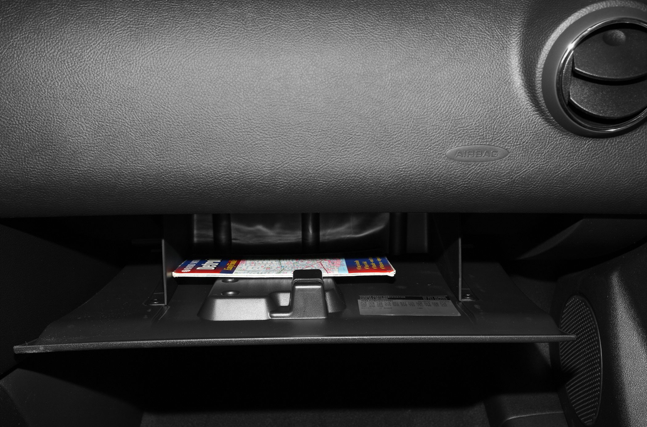 Open glove compartment with map inside in car interior