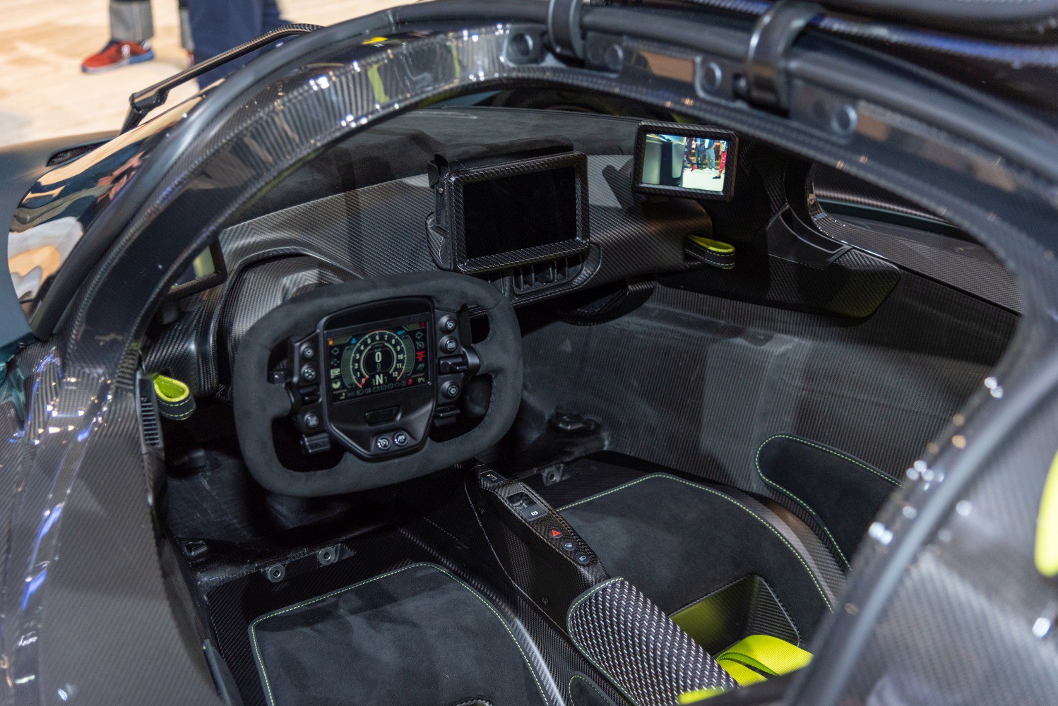 Racing-style steering wheel with digital displays in a carbon fiber cockpit