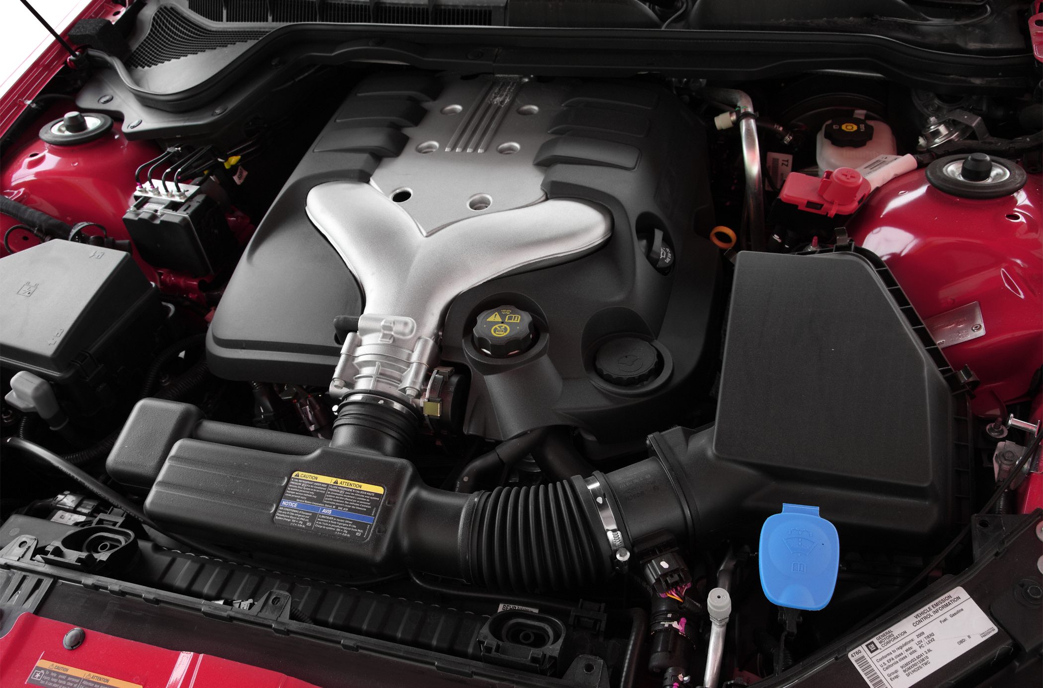 Detailed car engine bay with Y-shaped air intake cover and fluid caps