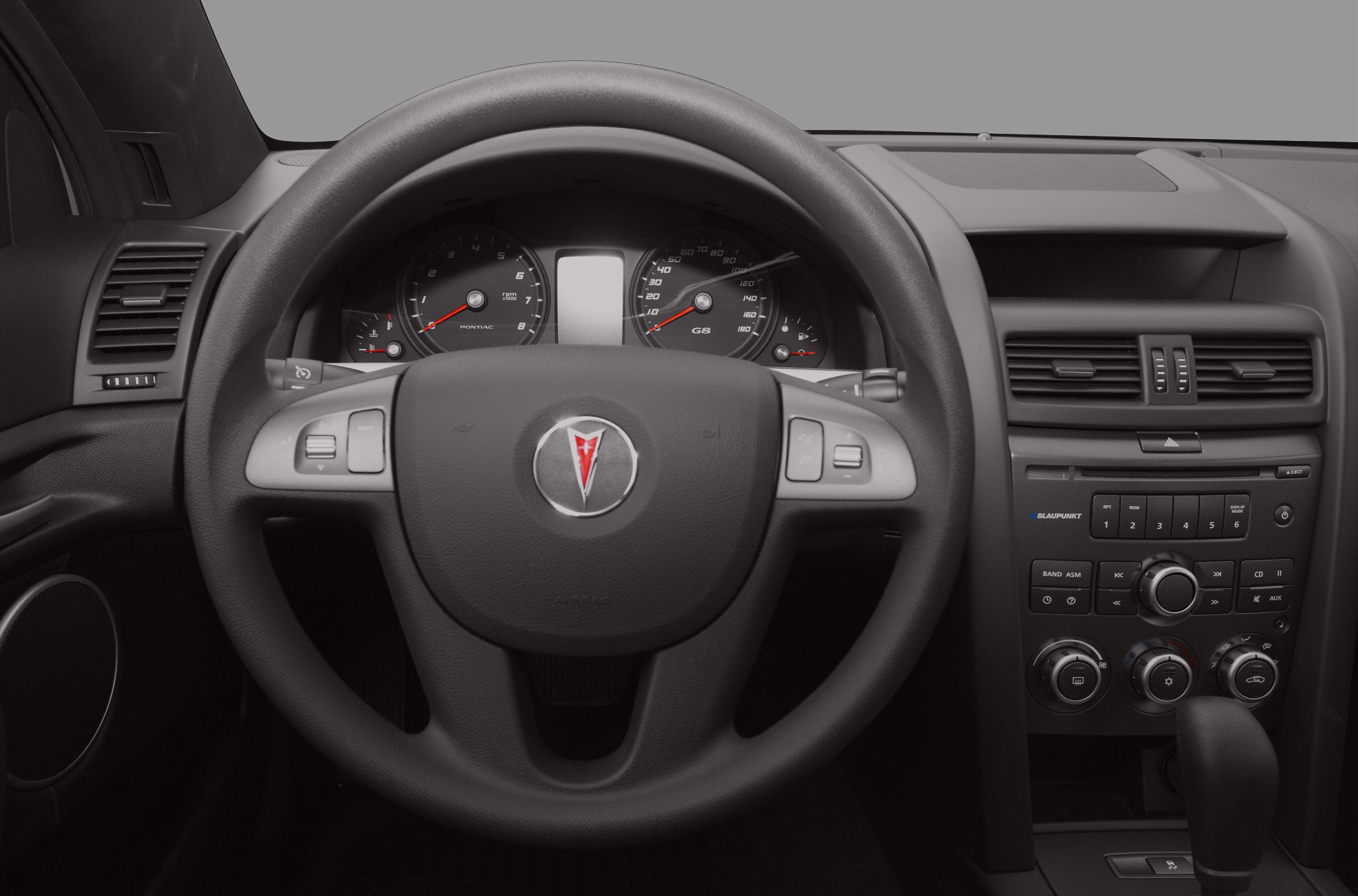 Close-up of steering wheel and dashboard with instrument cluster.