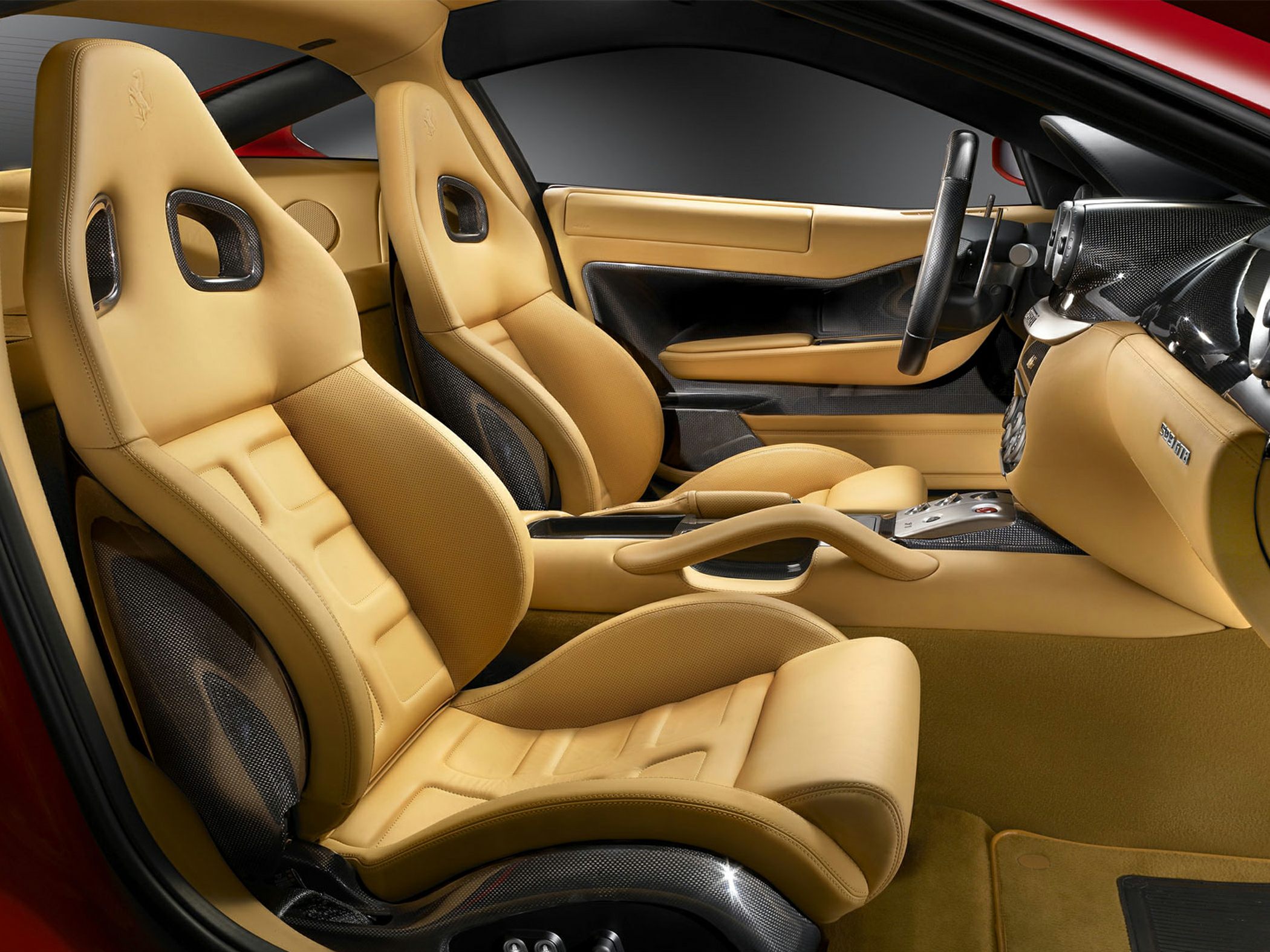 Beige leather racing seats with carbon fiber surrounds and dashboard accents