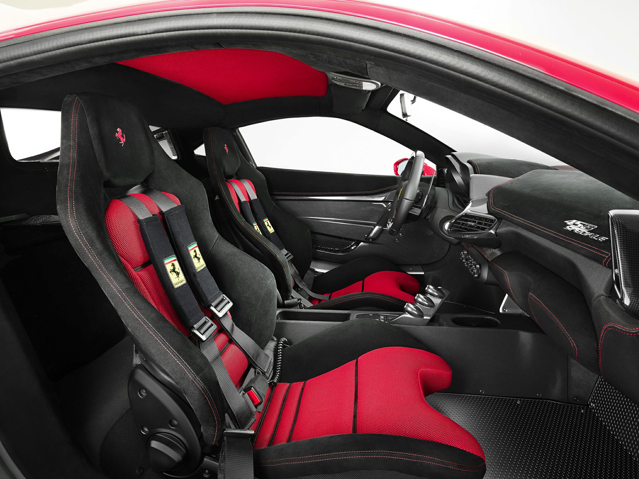 Red and black racing seats with harnesses, carbon fiber dashboard, stitched interior