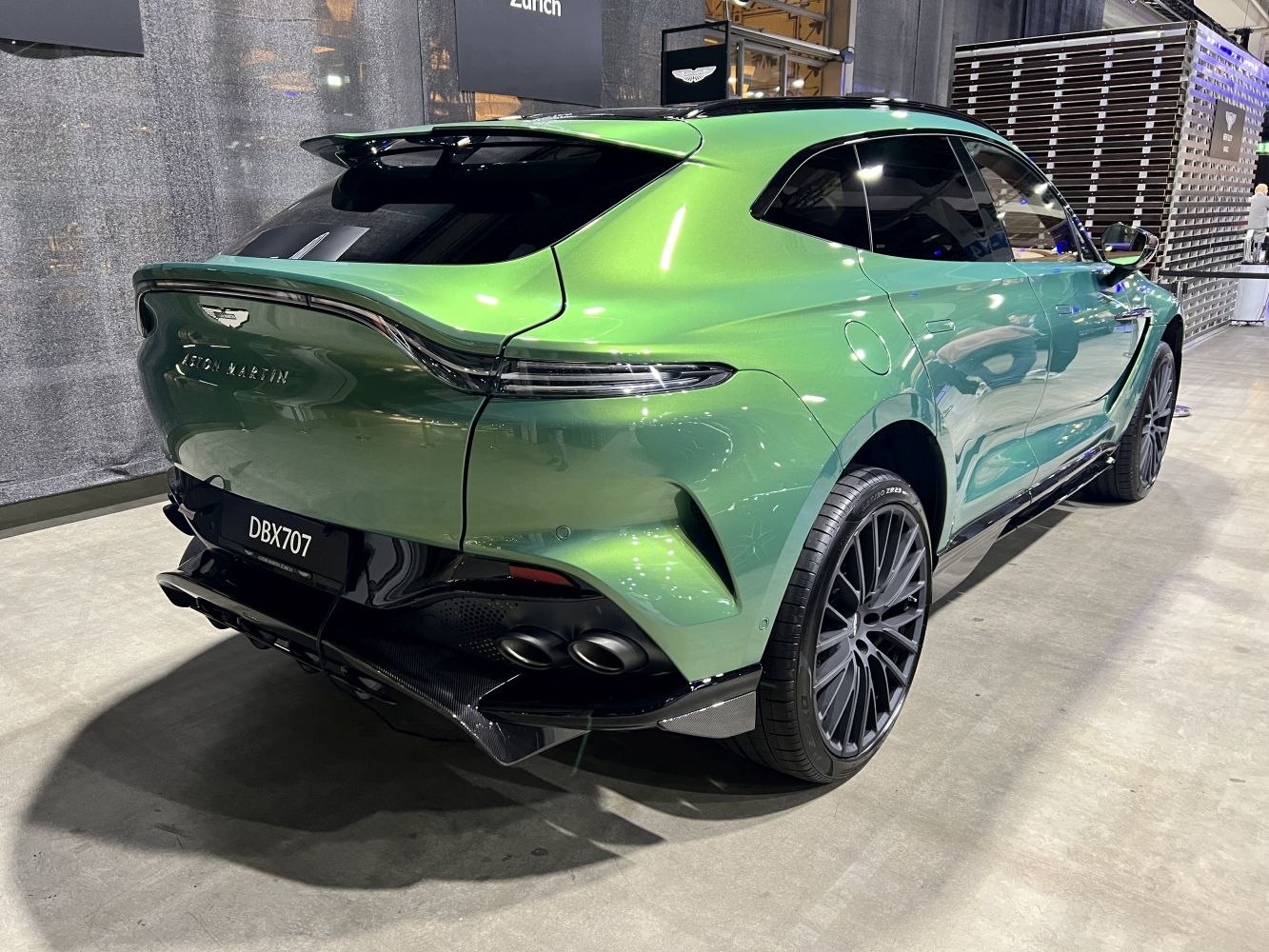 Green SUV rear with sleek taillights and quad exhaust pipes.