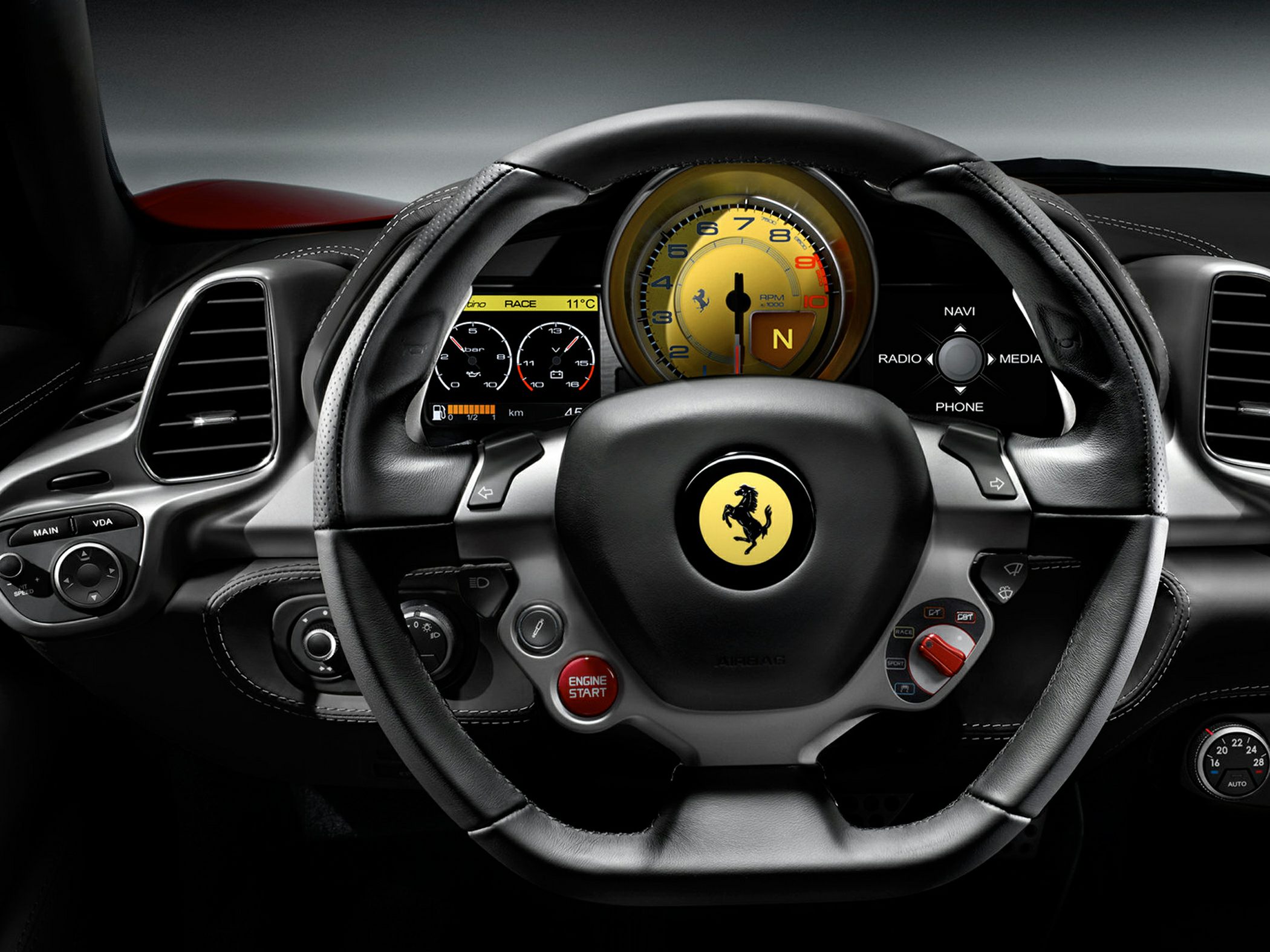 Close-up of steering wheel and yellow tachometer on a digital dashboard.