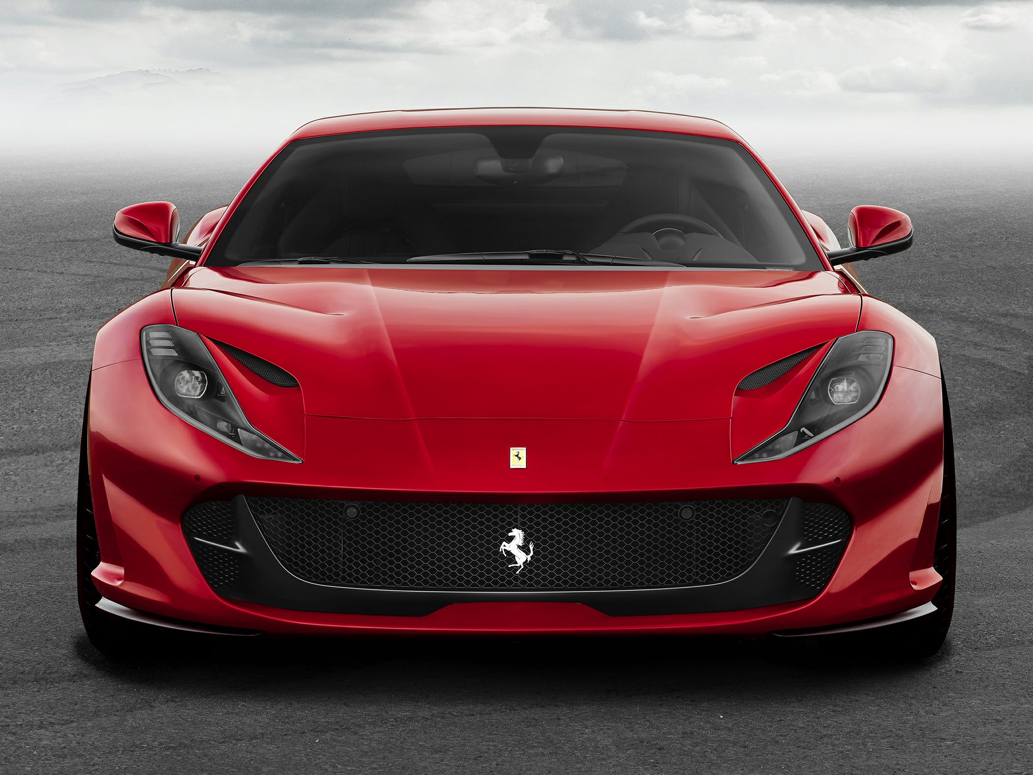 Red sports coupe with aerodynamic vents and honeycomb grille front view