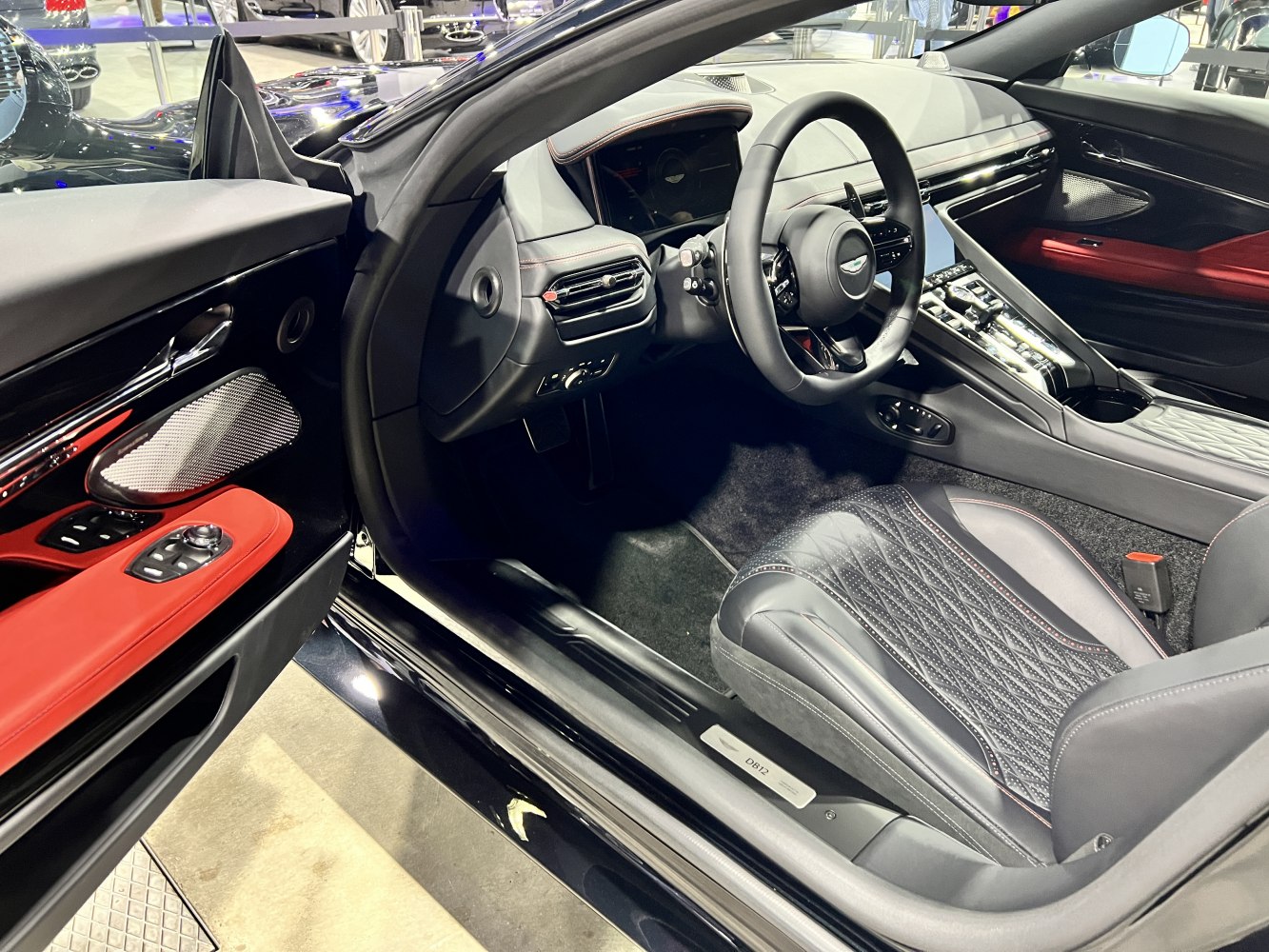 Quilted black leather seats with red accented door panel and modern digital dashboard.