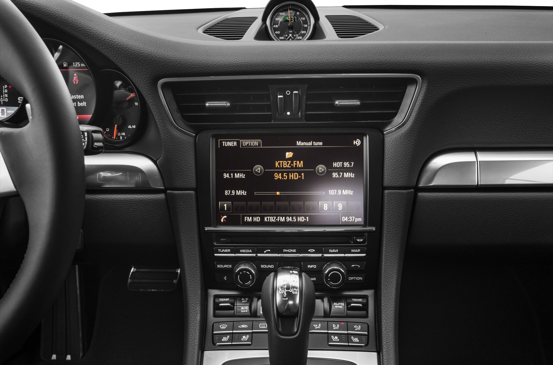 Center console with infotainment, climate controls, gear shifter, and analog clock on dashboard