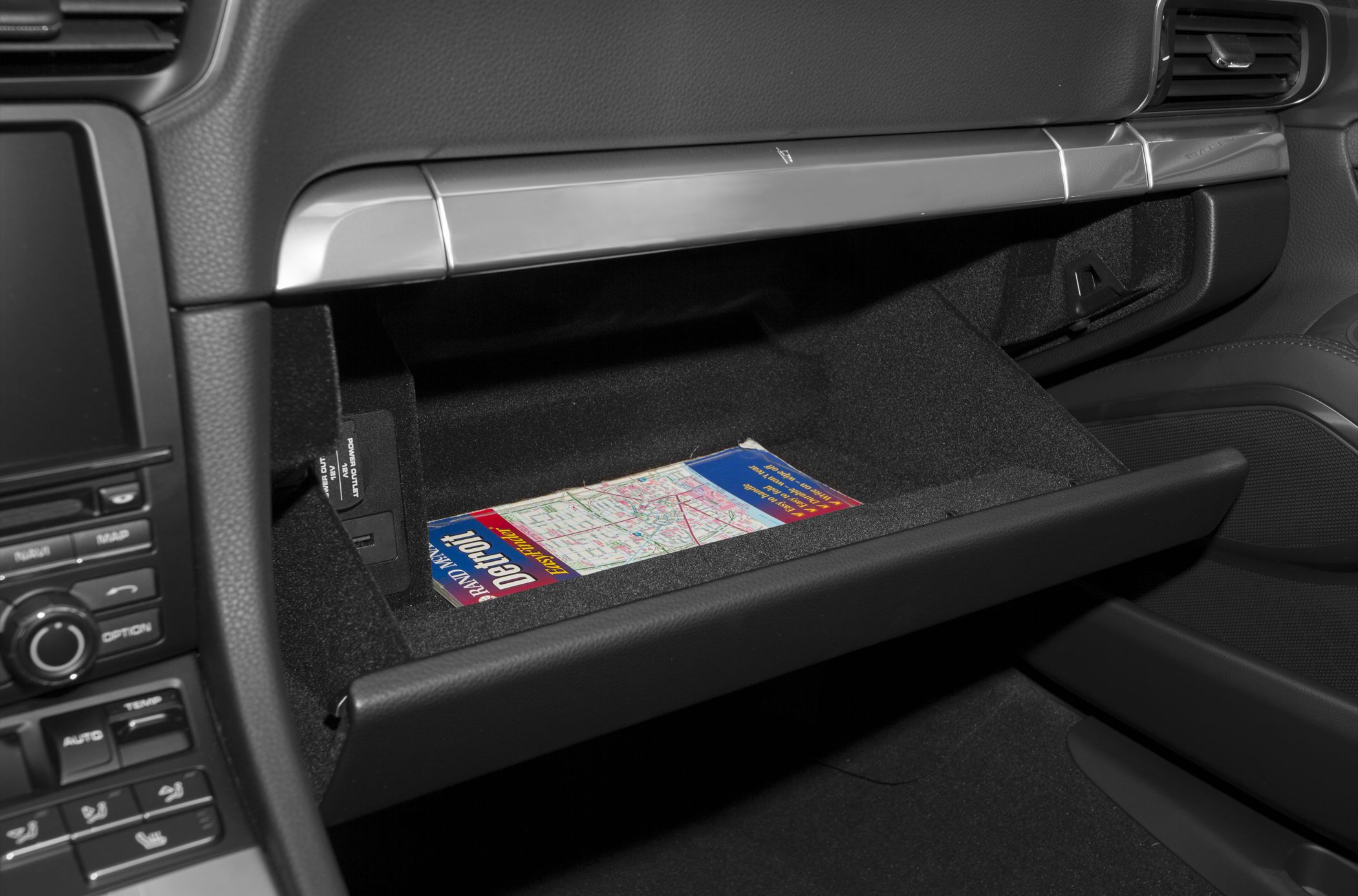 Open glove compartment with map inside car interior