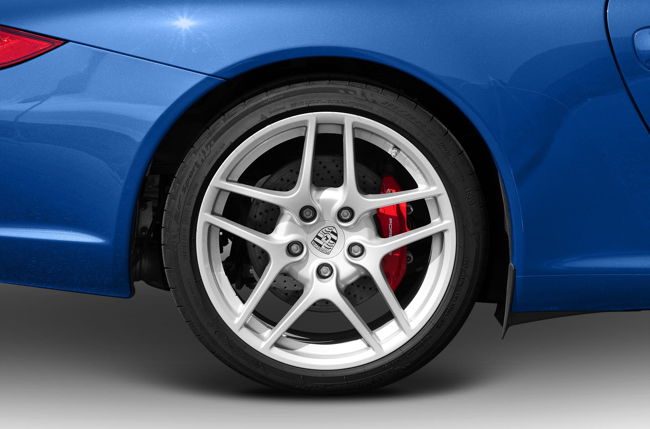 Silver sport wheel with red branded brake caliper on drilled disc