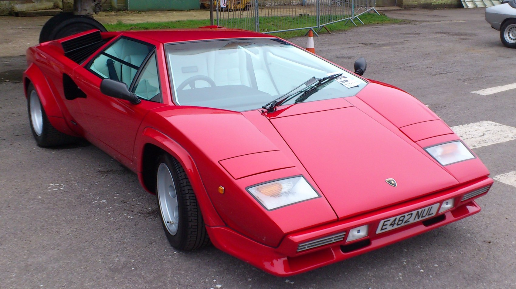 Red angular sports car with pop-up headlights and wide tires