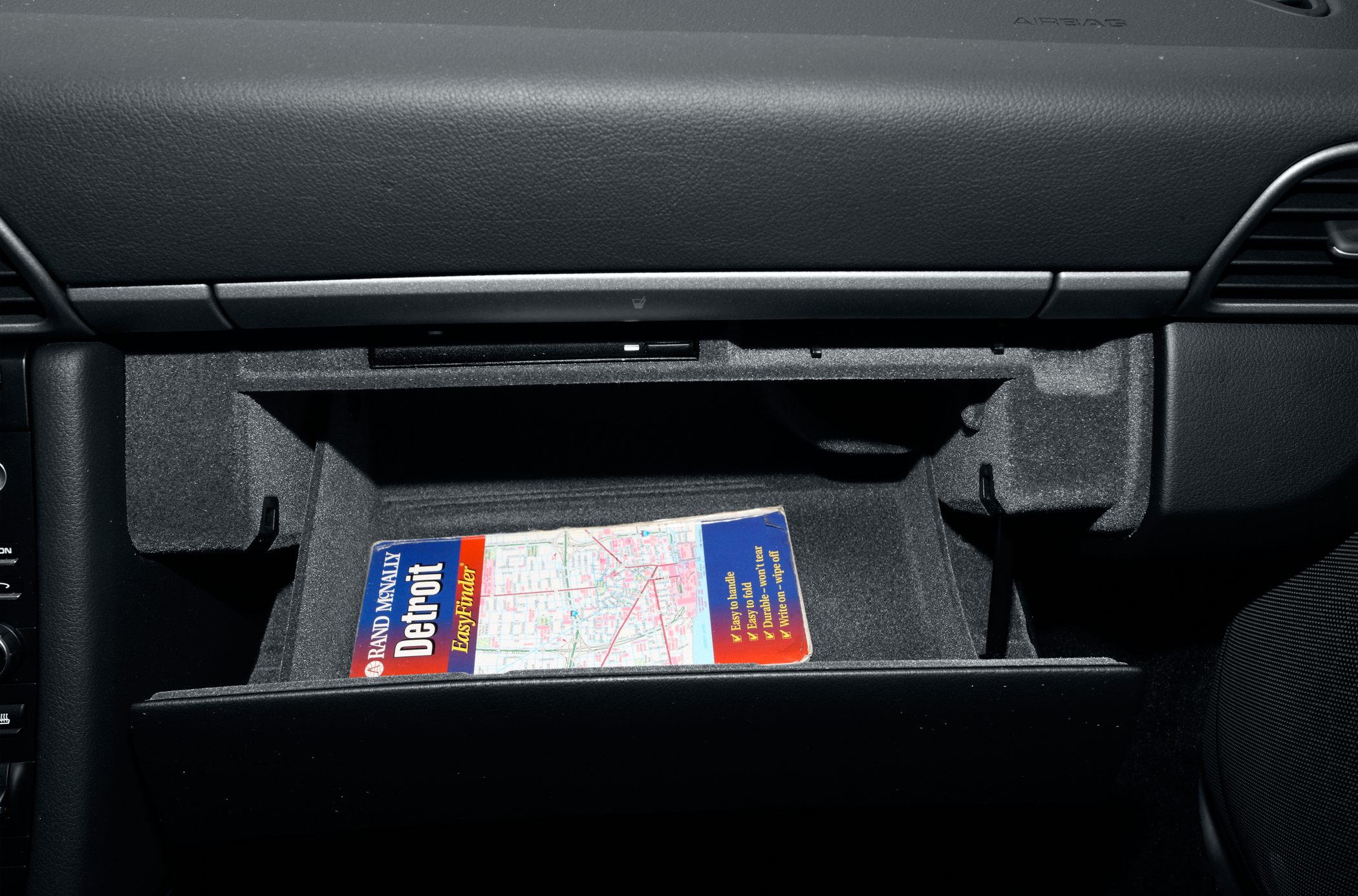 Open glove compartment with map inside car interior
