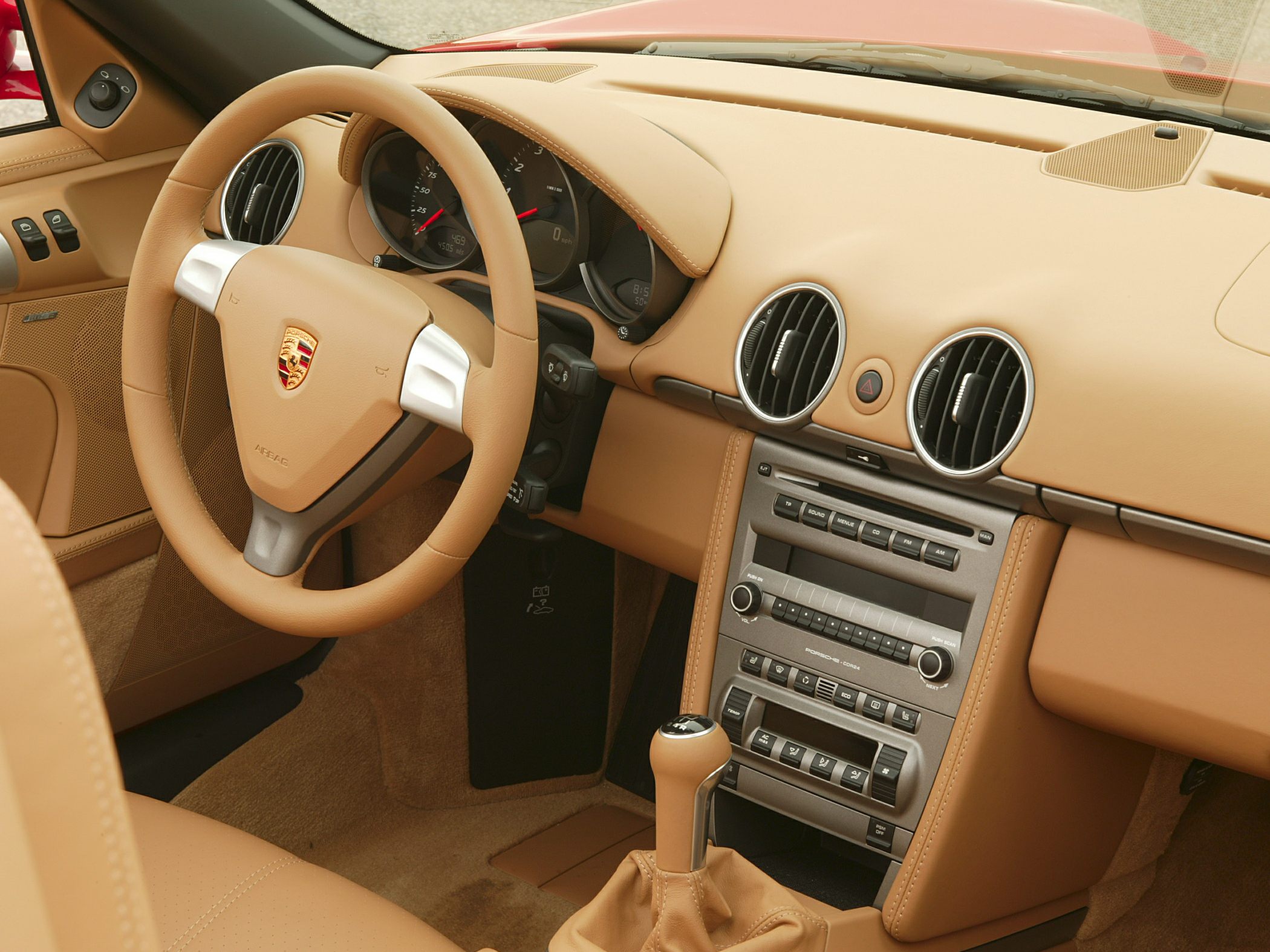 Beige leather steering wheel, dashboard with round air vents, manual gear shift