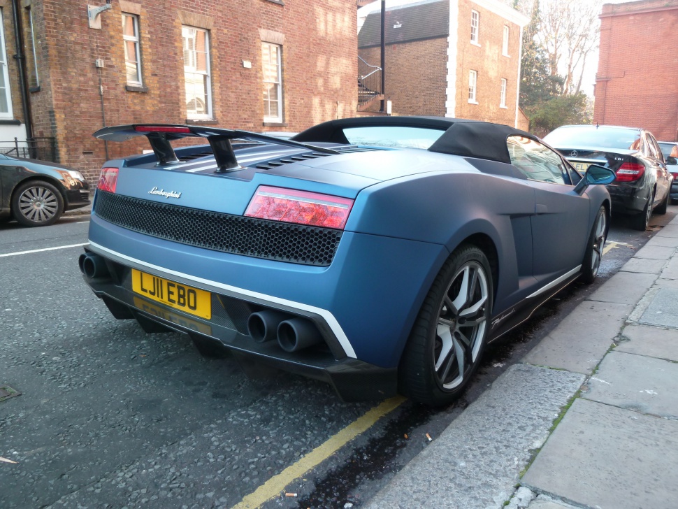 Rear view with taillights, dual exhaust, rear wing spoiler, and convertible top