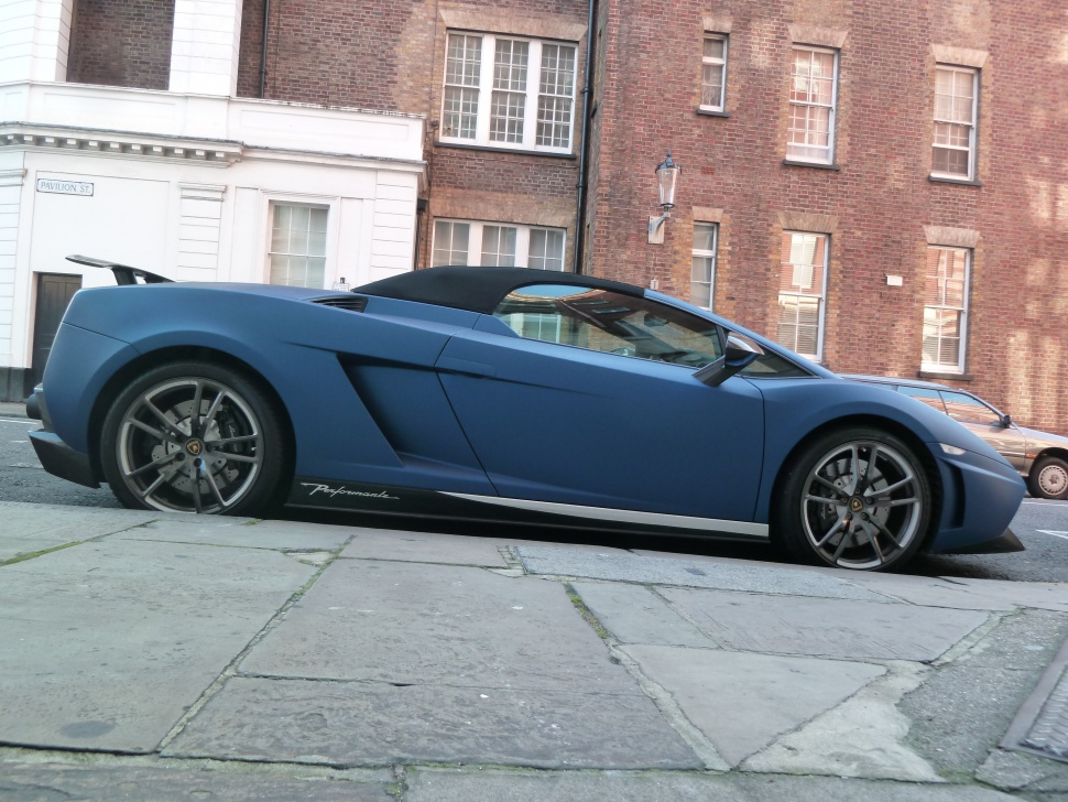 Matte blue convertible sports car with soft top and alloy wheels side profile