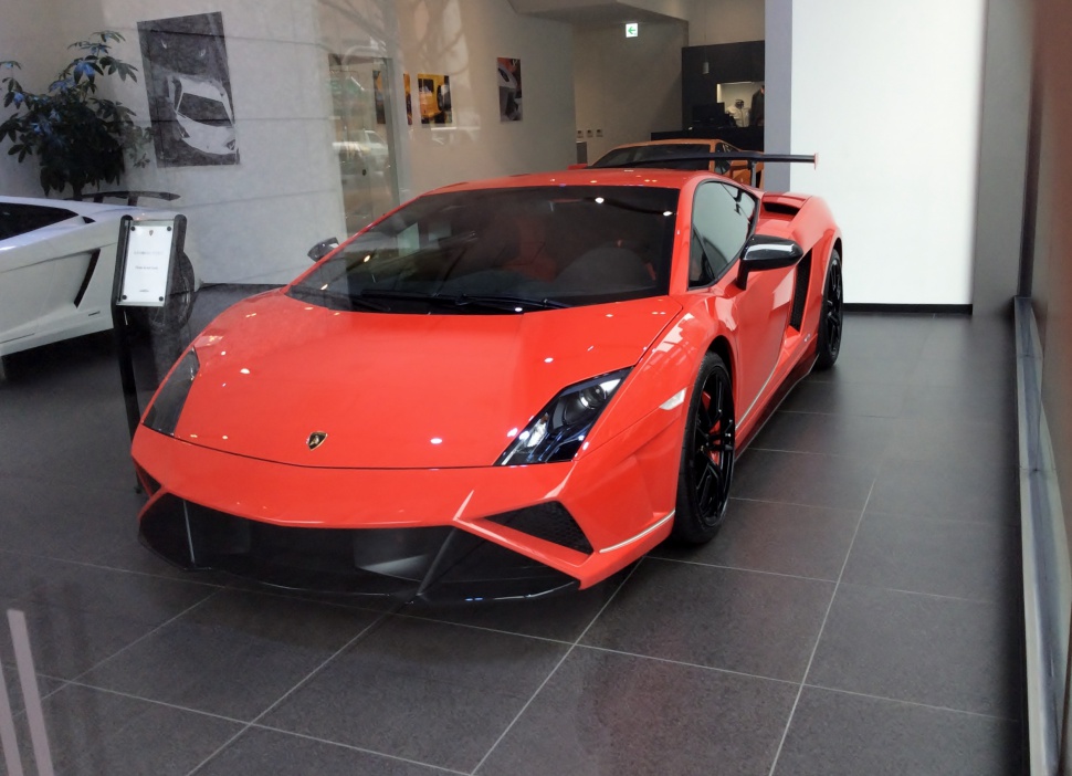 Bright orange sports car with large rear wing, aerodynamic front.