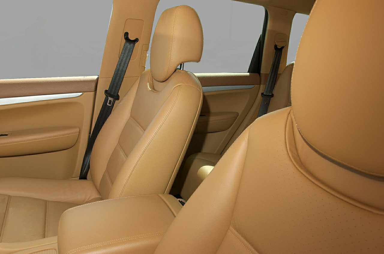Tan leather front and rear seats with seat belts inside a vehicle