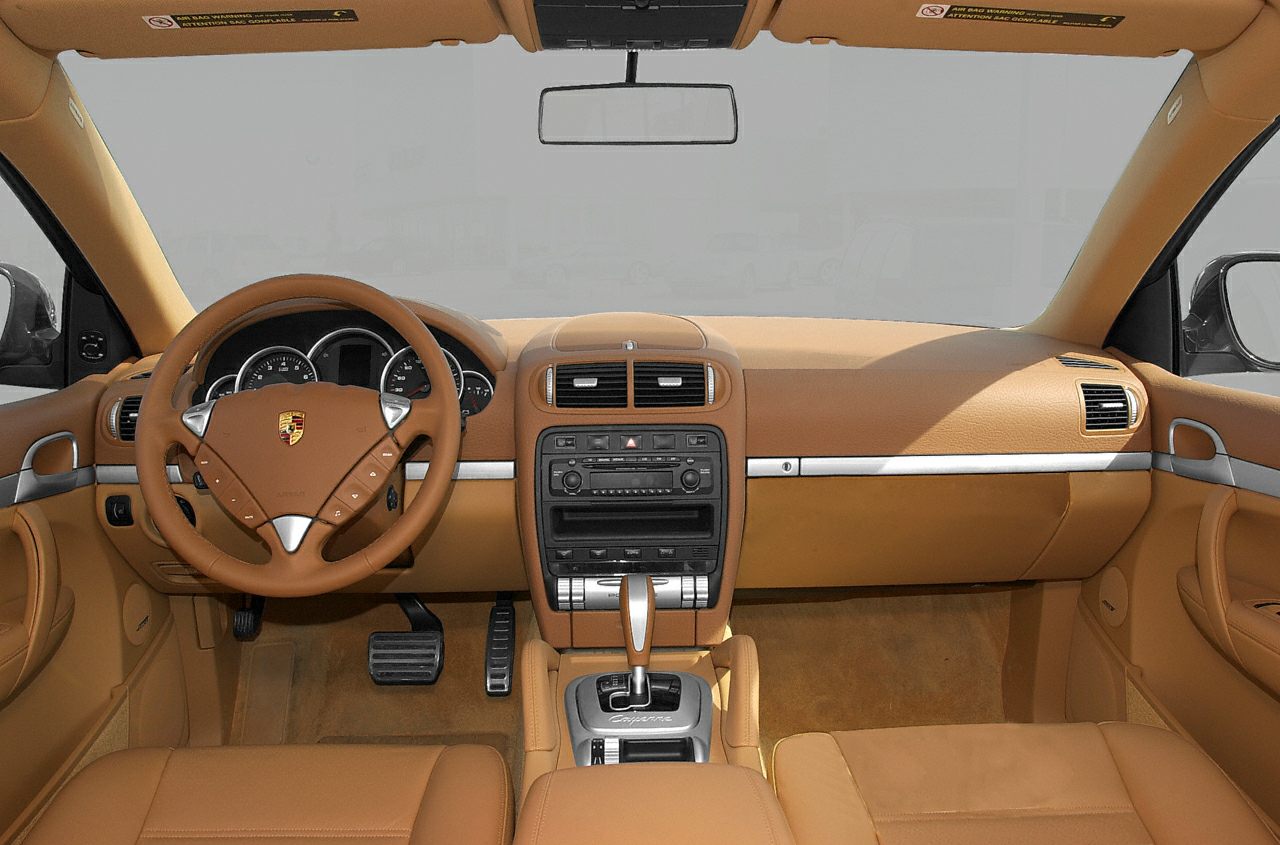 Tan leather dashboard and steering wheel with central console and pedals.