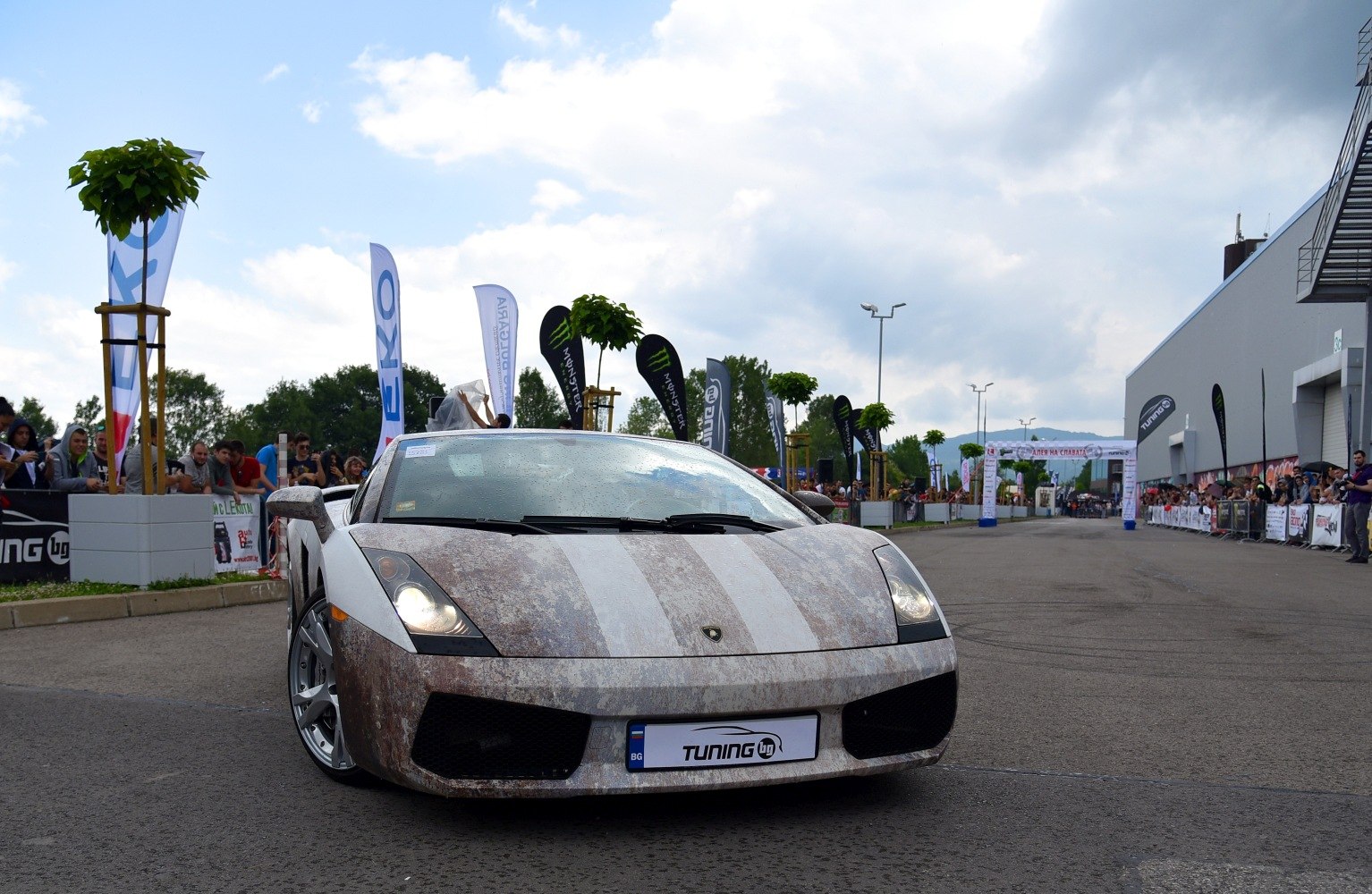 Front view of a Lamborghini coupe with patina style wrap and headlights on.